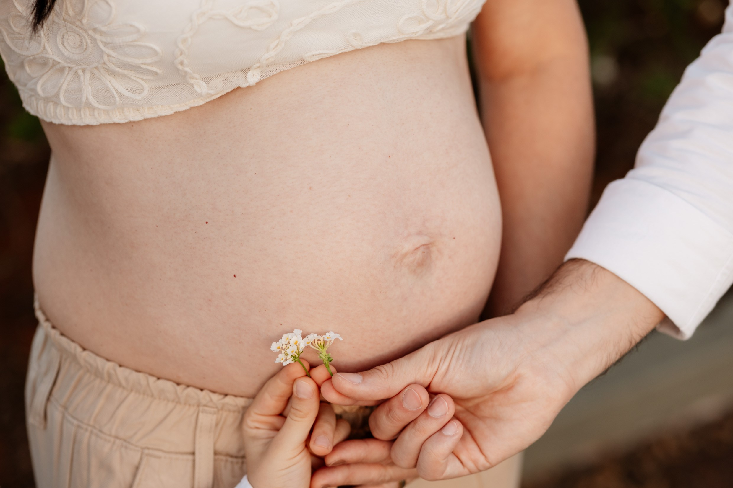 Detalhe das mãos da família reunidas em torno da barriga.