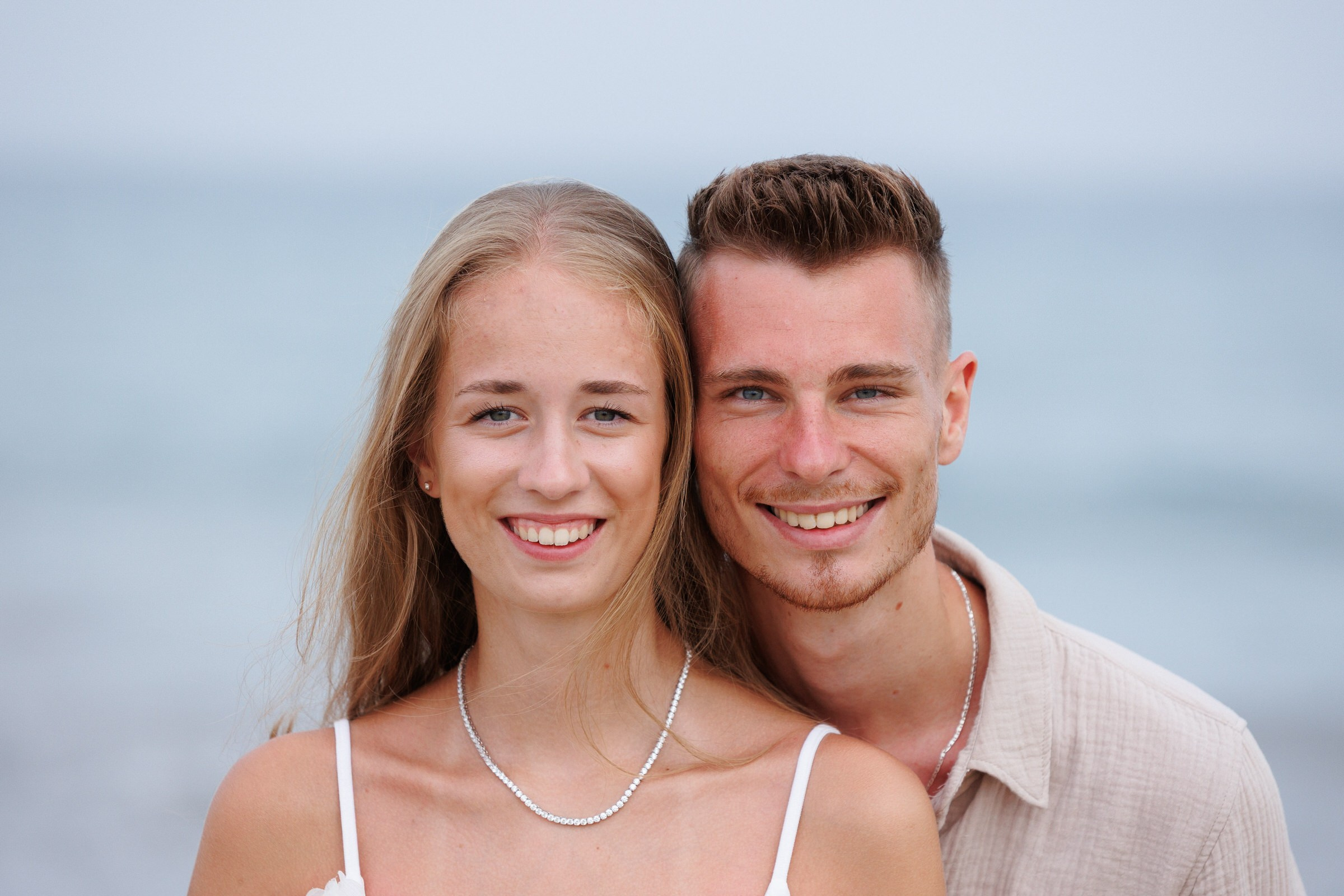 A sun-lit beach portrait of a happy couple in flowing attire, full of love and laughter, shot by Gran Canaria freelancer Slavik Robtsenkov during a romantic vacation.