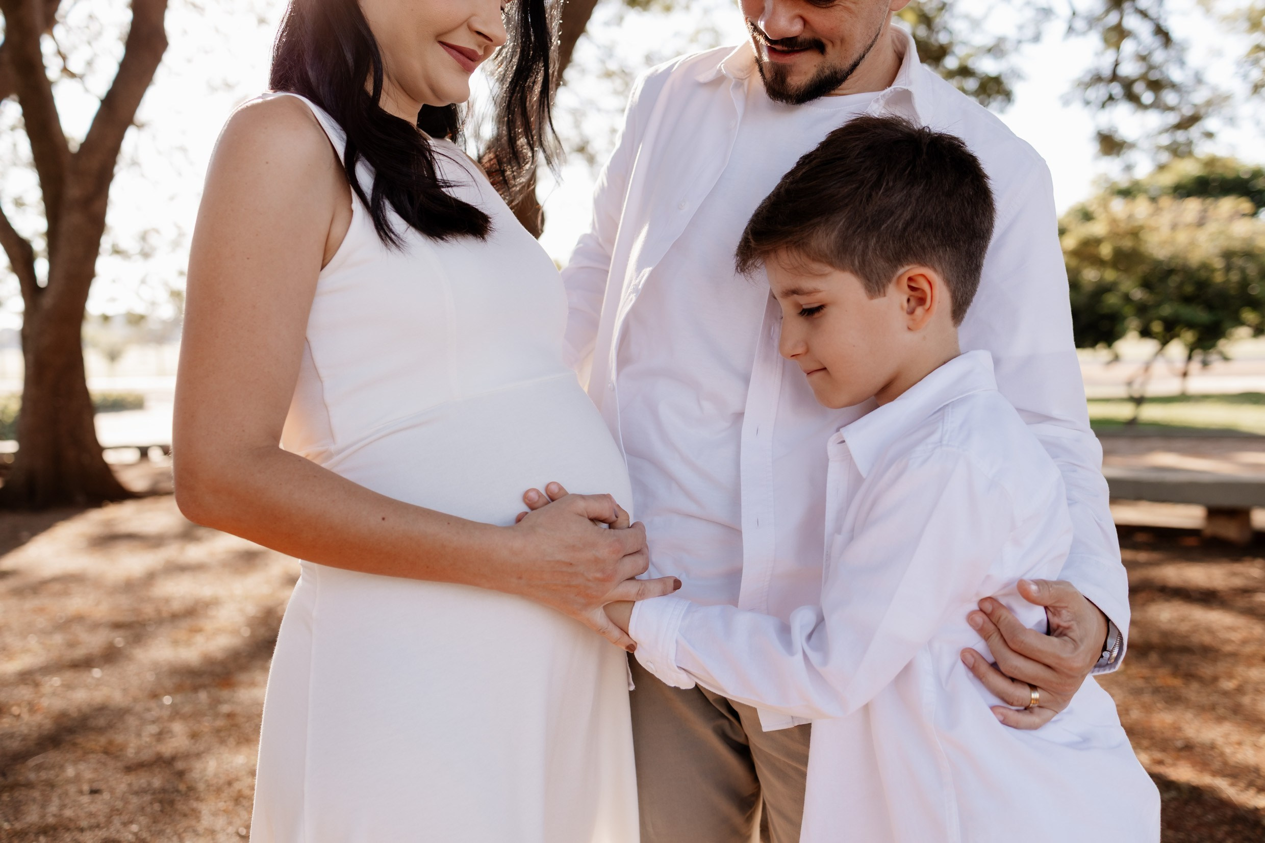 Detalhe da barriga da gestante com o filho fazendo carinho