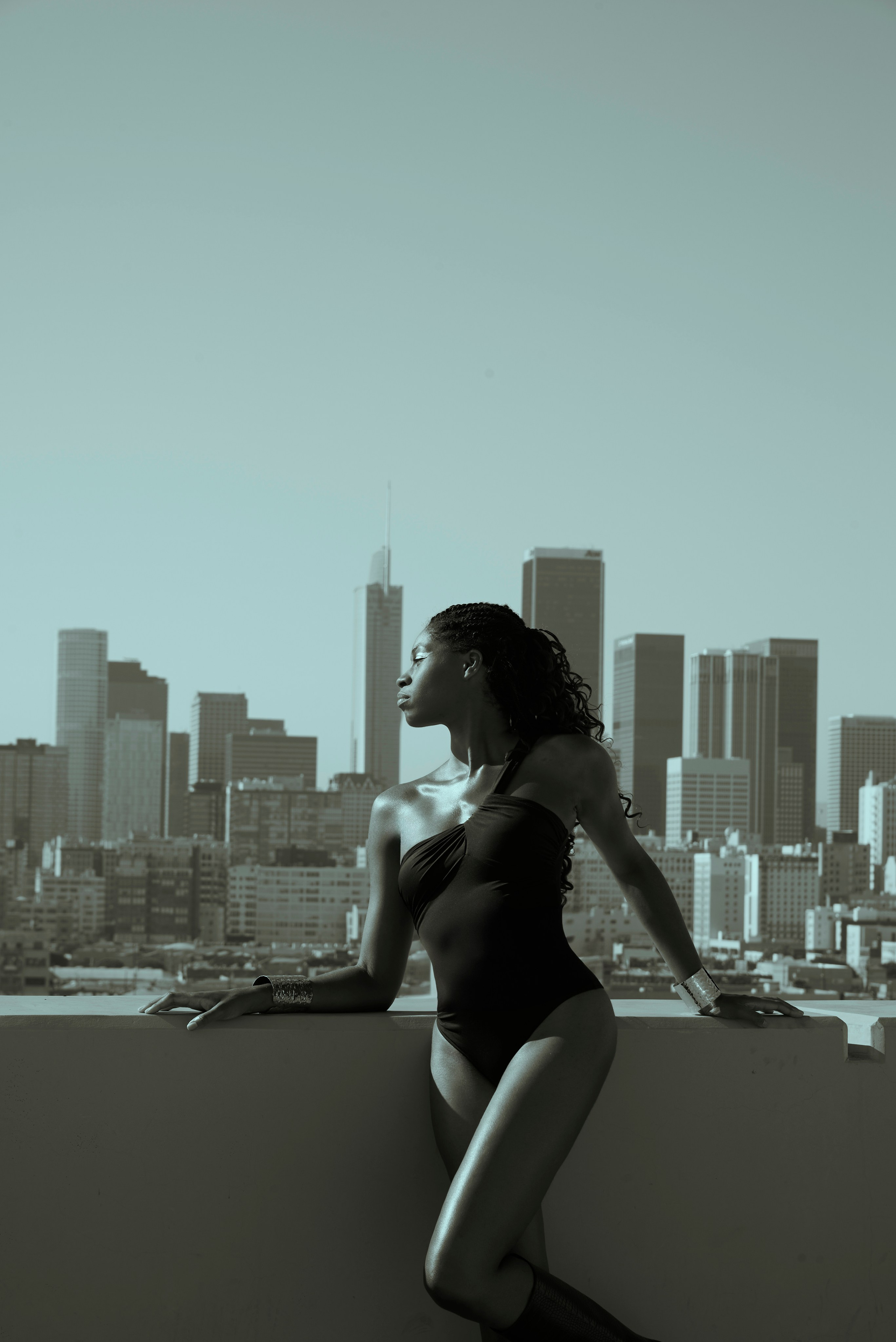 Cinematic fashion shot with deep shadows and downtown skyline