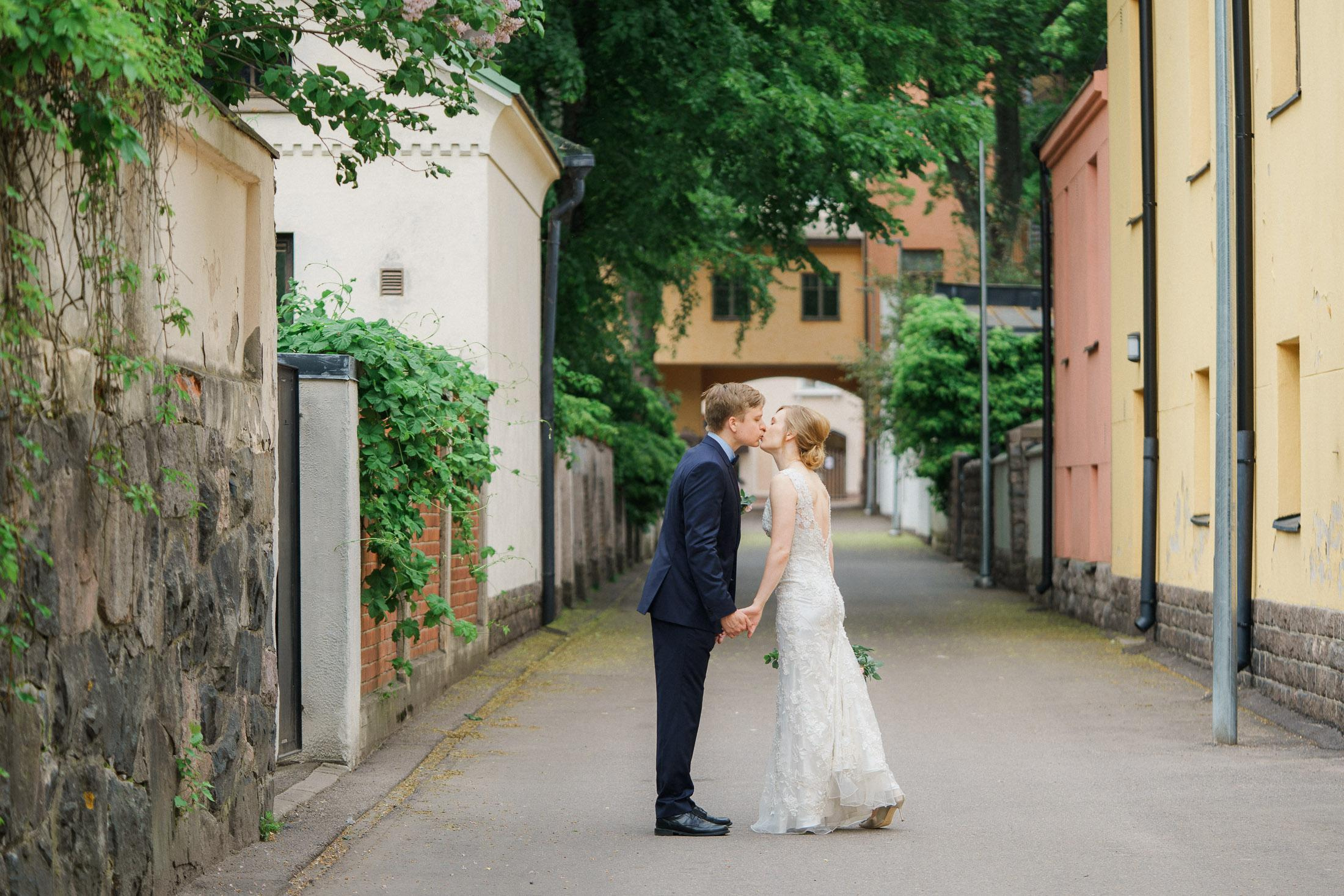 Hääpotretti jossa morsian ja sulhanen suutelevat kadulla