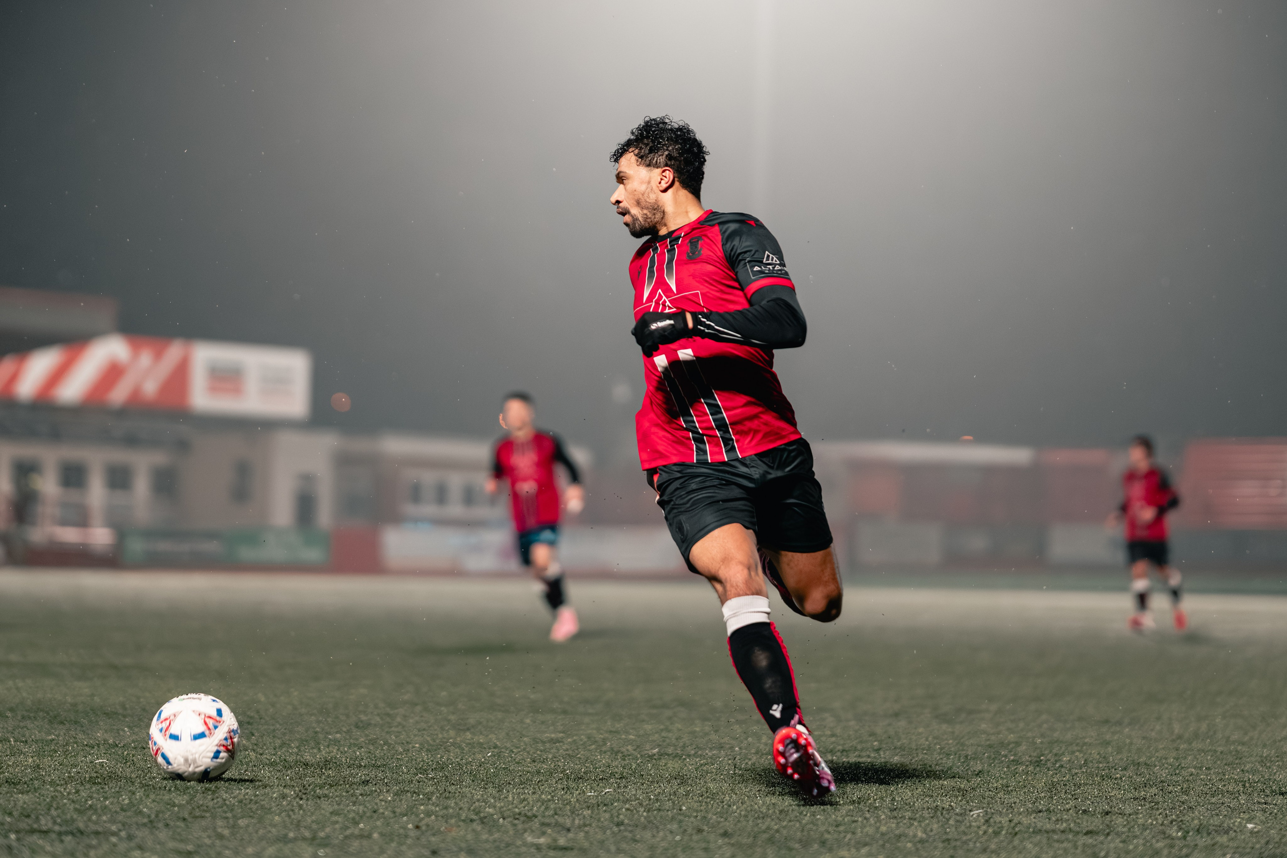 Luke Fairlamb of Tamworth runs with the ball under the floodlights in the Birmingham Senior Cup match vs Alvechurch at The Lamb Ground, Tamworth, 3 February 2026.