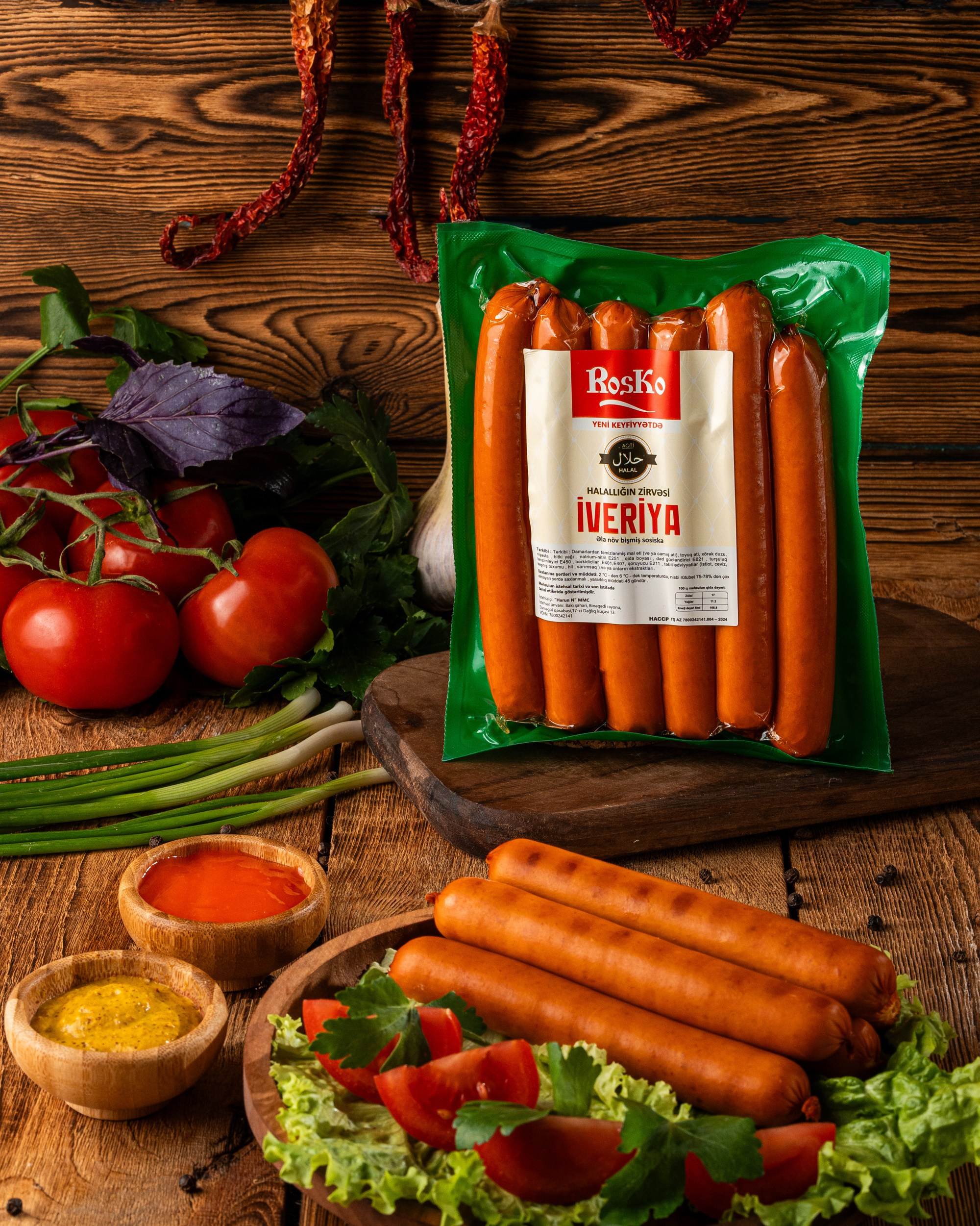 RosKo İveriya halal kolbasa məhsulu, yaşıl qablaşdırmada, təzə tərəvəz və souslarla rustik ağac fonunda