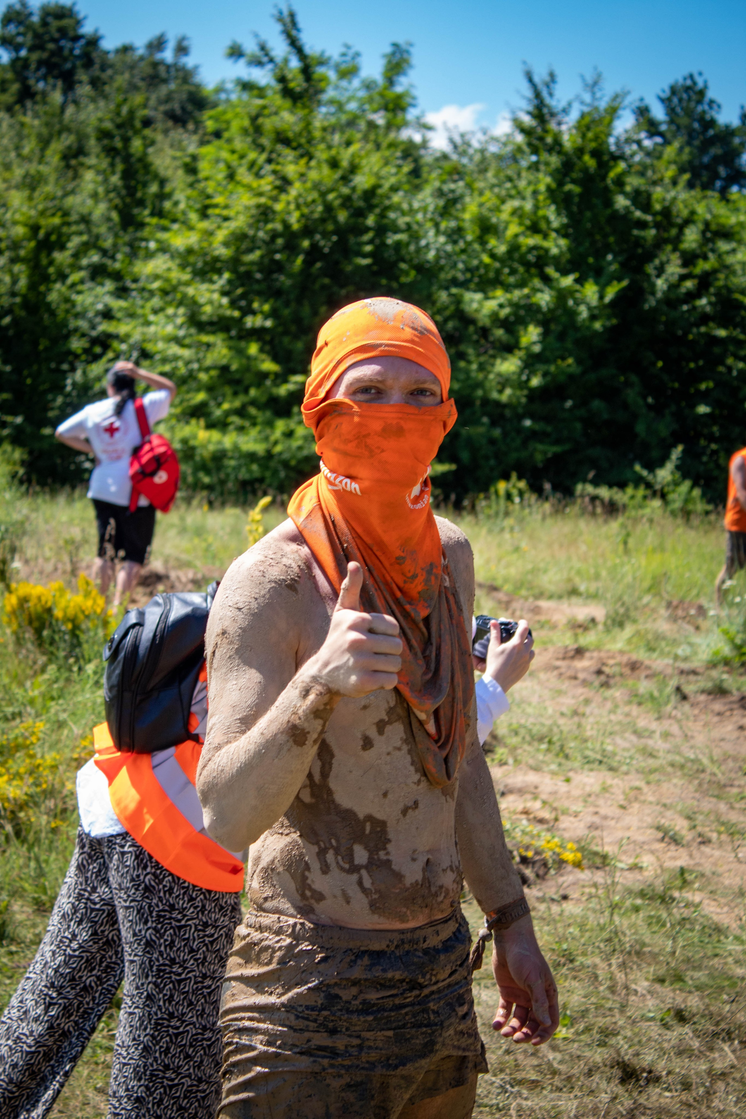 Man wearing an orange bandana and event shirt, smiling after completing a sports challenge.