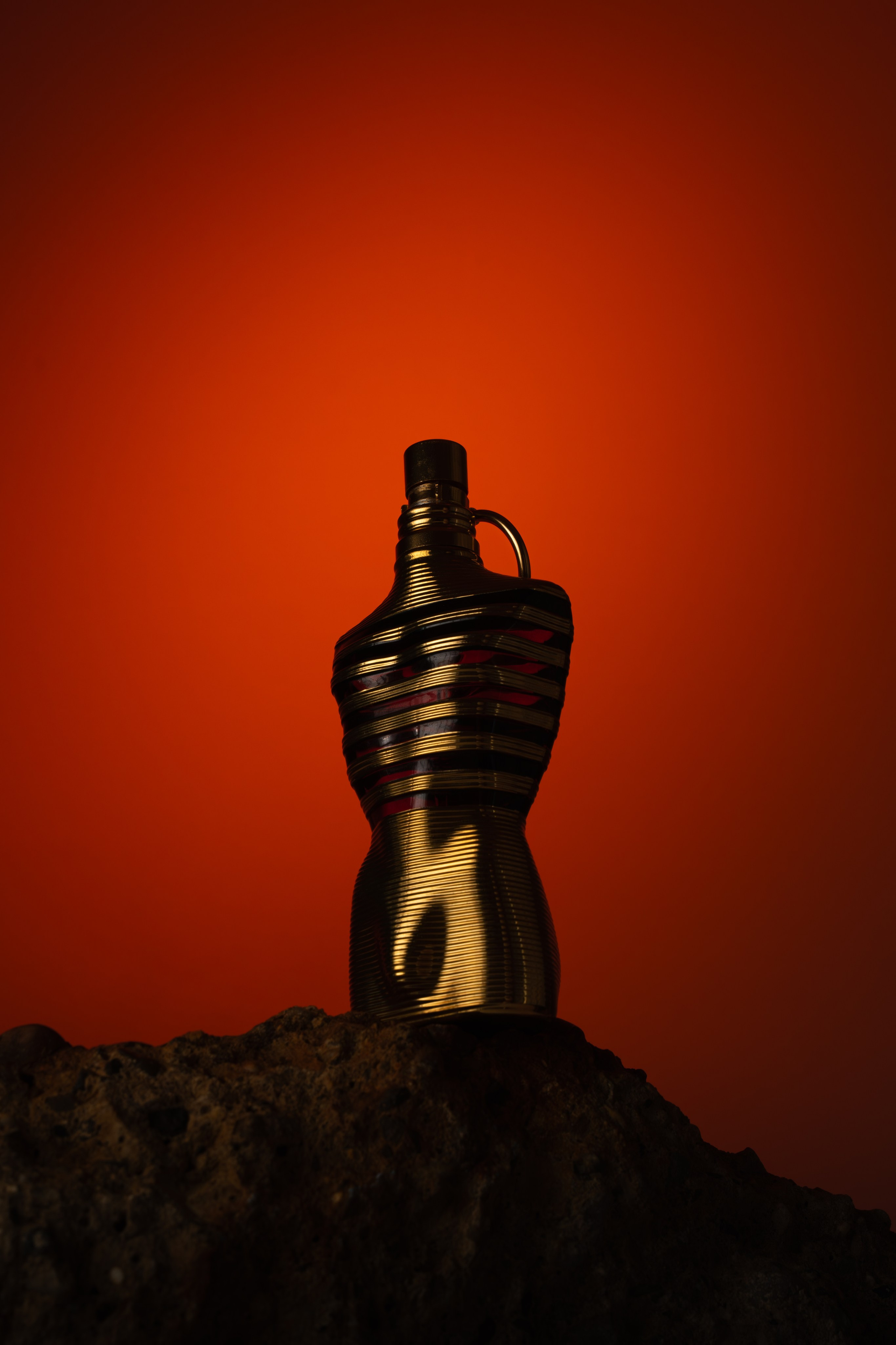 Designer perfume bottle against bold red light — cinematic still life composition by Jay Soundo.