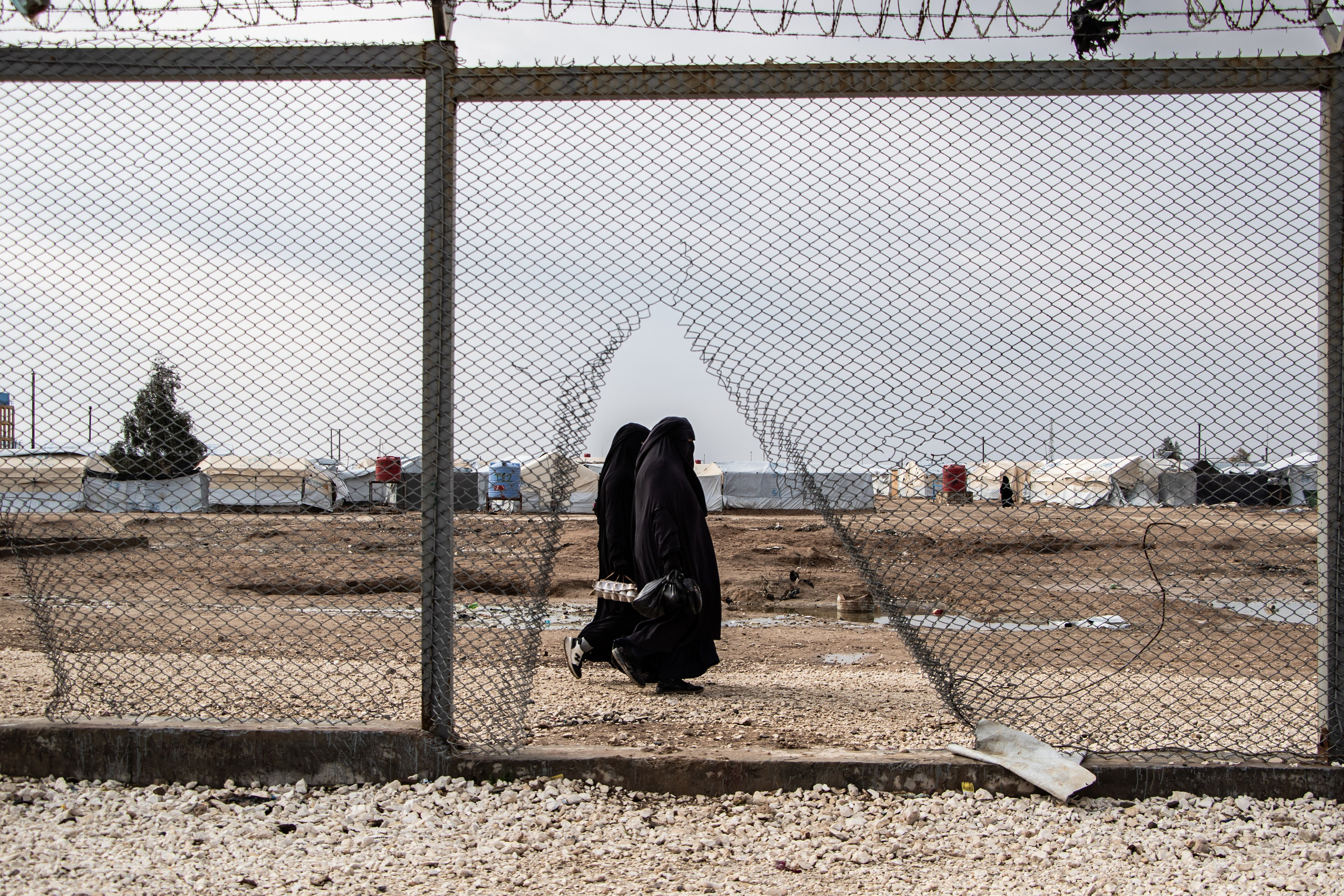 Kurdistan Syrien Camps d'Al-Hol 11 février 2025 : deux femmes marchent contre les grilles du camps des prisonniers de Daesh.