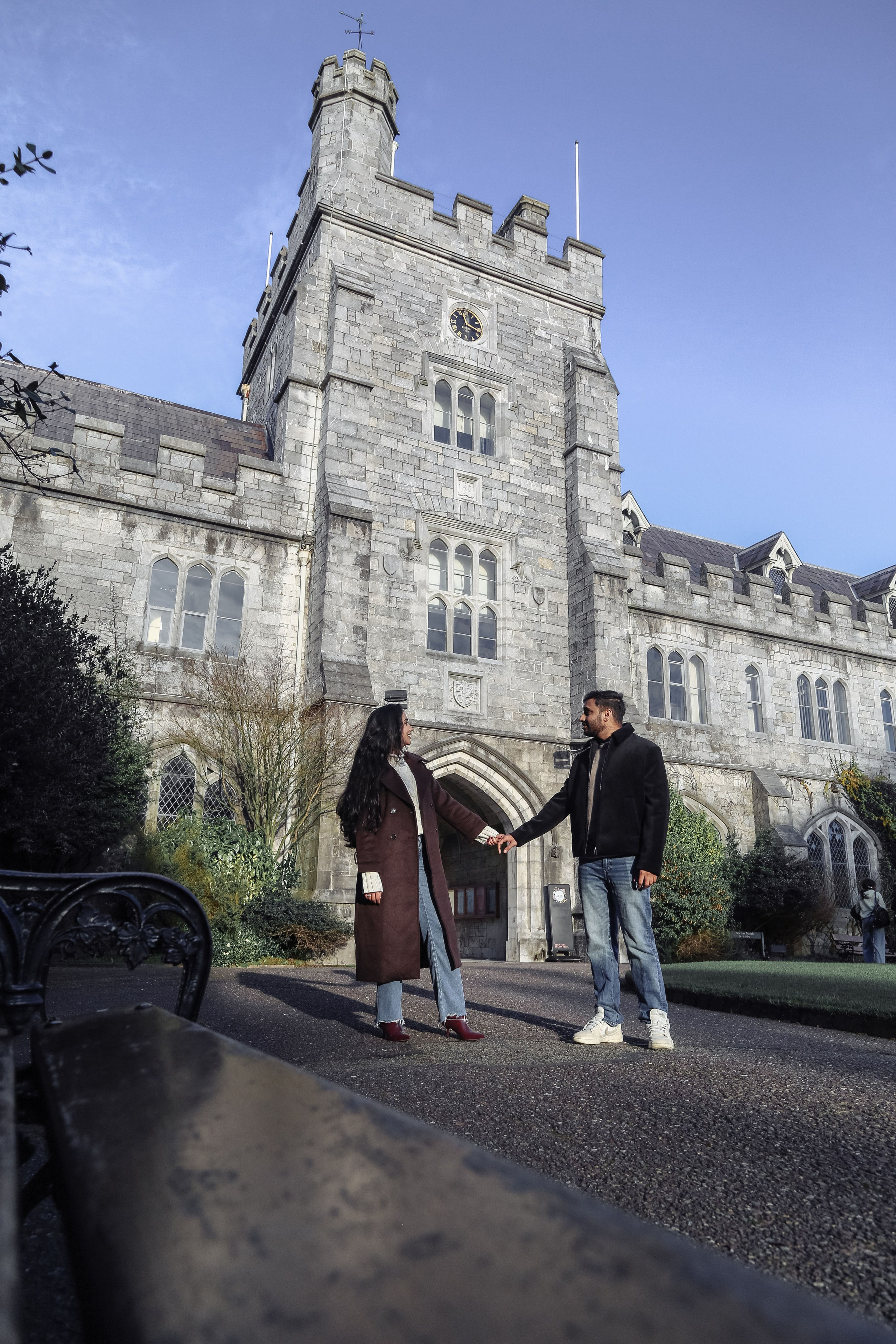 A wide architectural portrait combining historic surroundings with relaxed body language and gentle interaction.