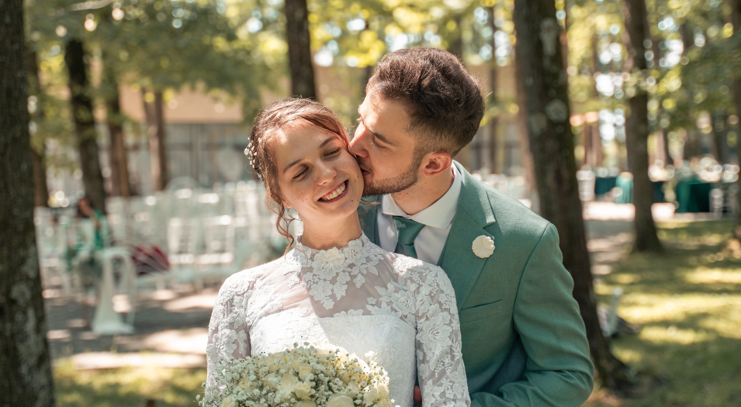 Mire sărutând mireasa pe obraz, nuntă în aer liber, cadru romantic în pădure, fotografii de cuplu naturale București, incadru.ro.