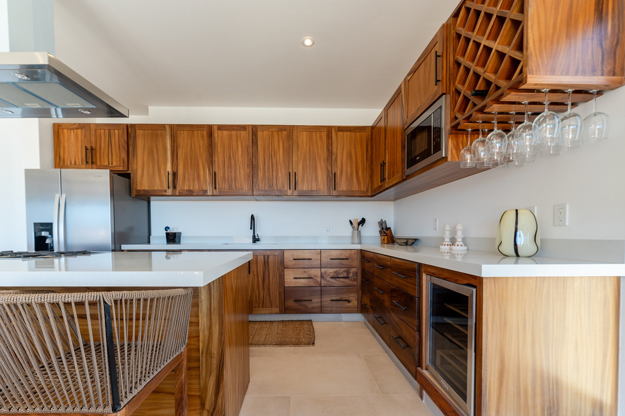 Minimalist kitchen details in Los Cabos – wooden cabinets, wine cooler, microwave and glassware, luxury property photography