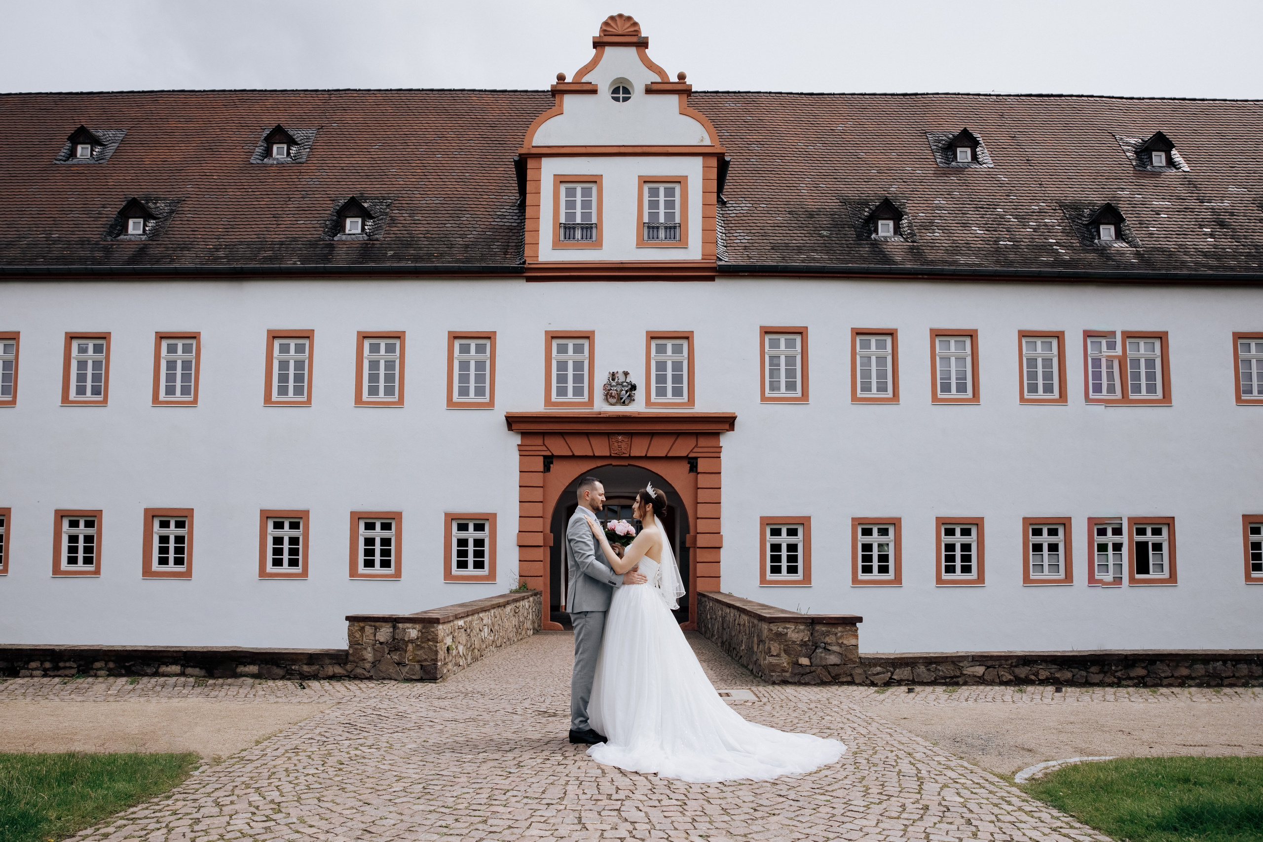 Der Bräutigam und die Braut stehen vor dem Schloss Heusenstamm.