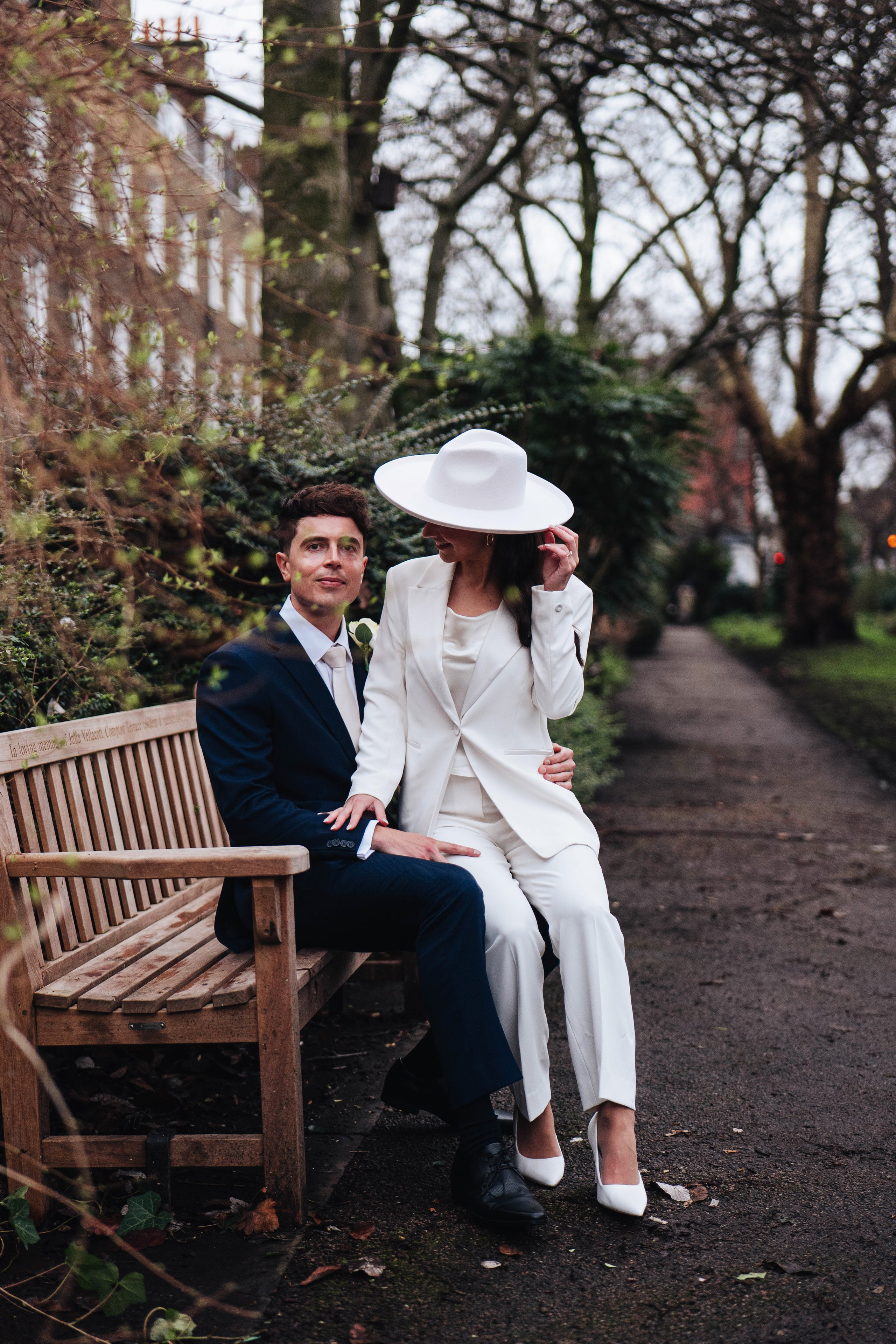 Stylish wedding in Islington, white women costume and white hat, sitting on a bench