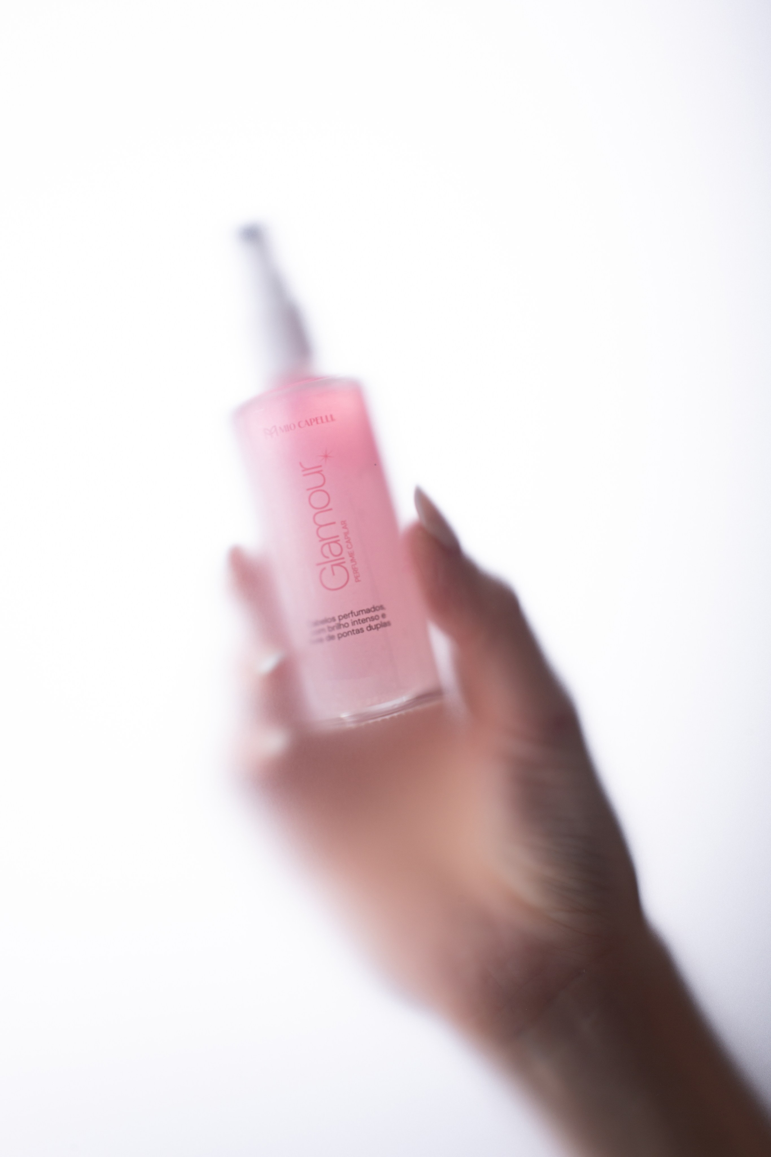 A minimalist glass bottle of hair serum in the hands of model. Professional product photo. 
