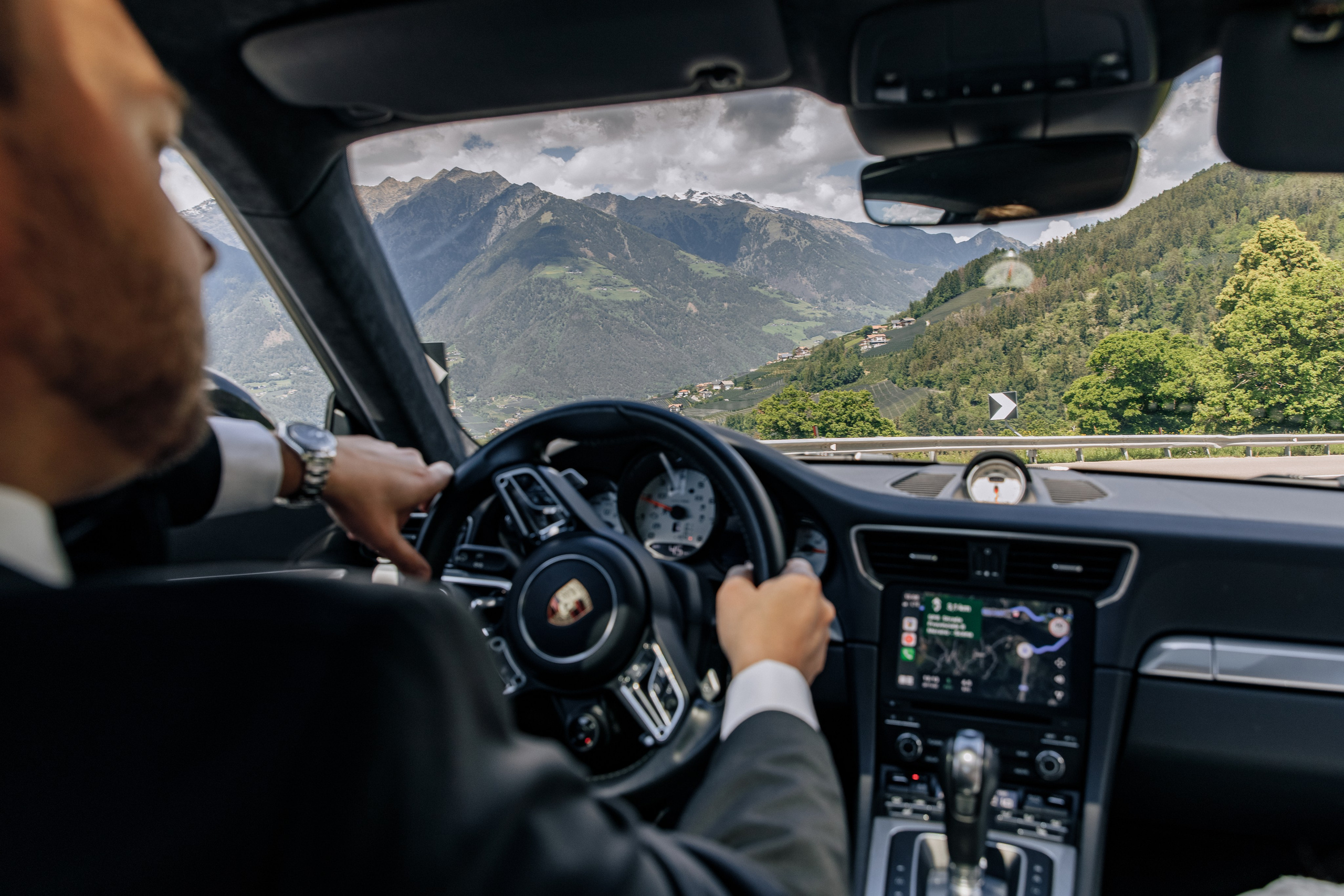 Der Bräutigam fährt in einem Porsche durch die malerischen Berglandschaften.