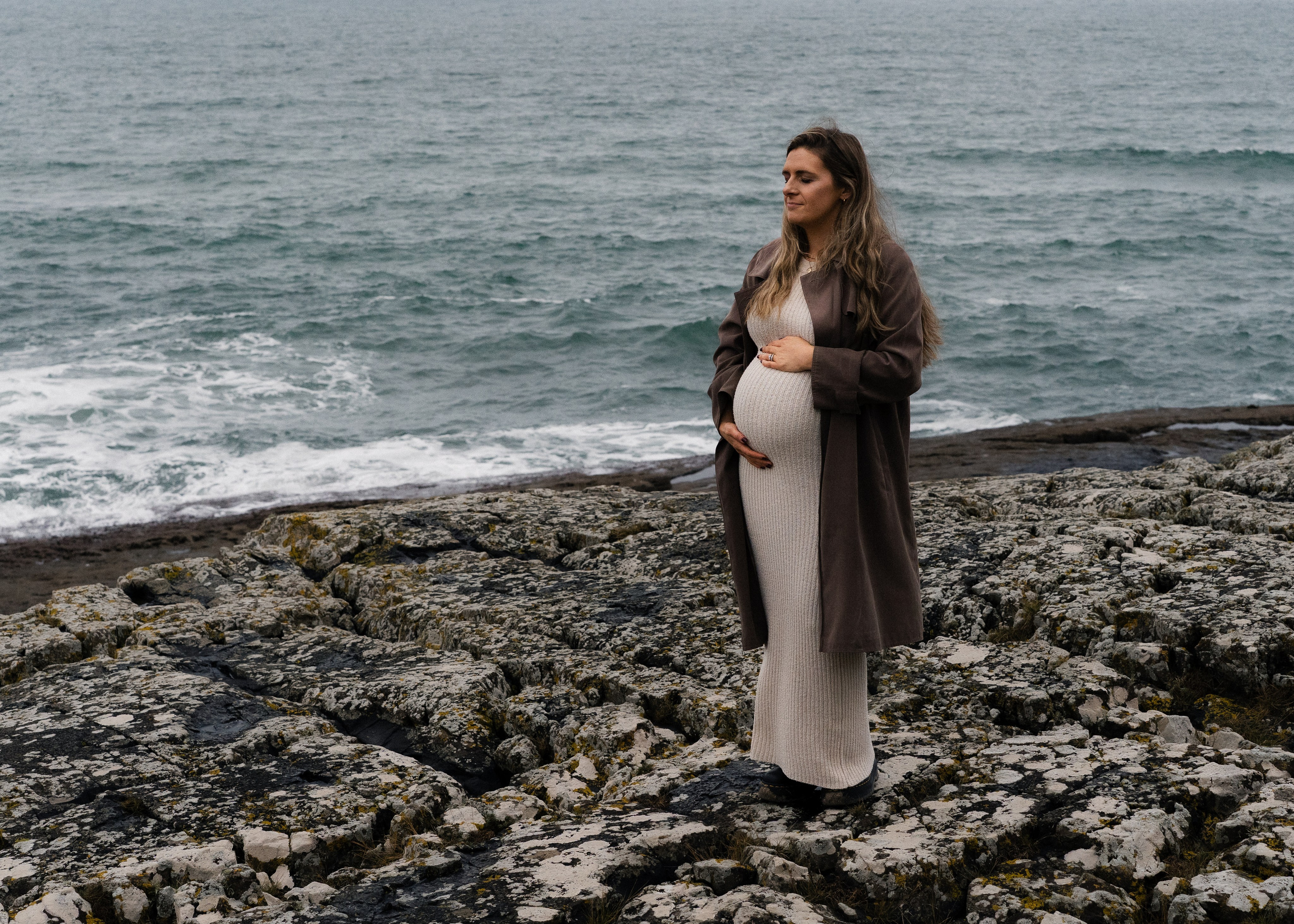 Pregnant woman by the sea during a natural maternity photography session on the North East coast.