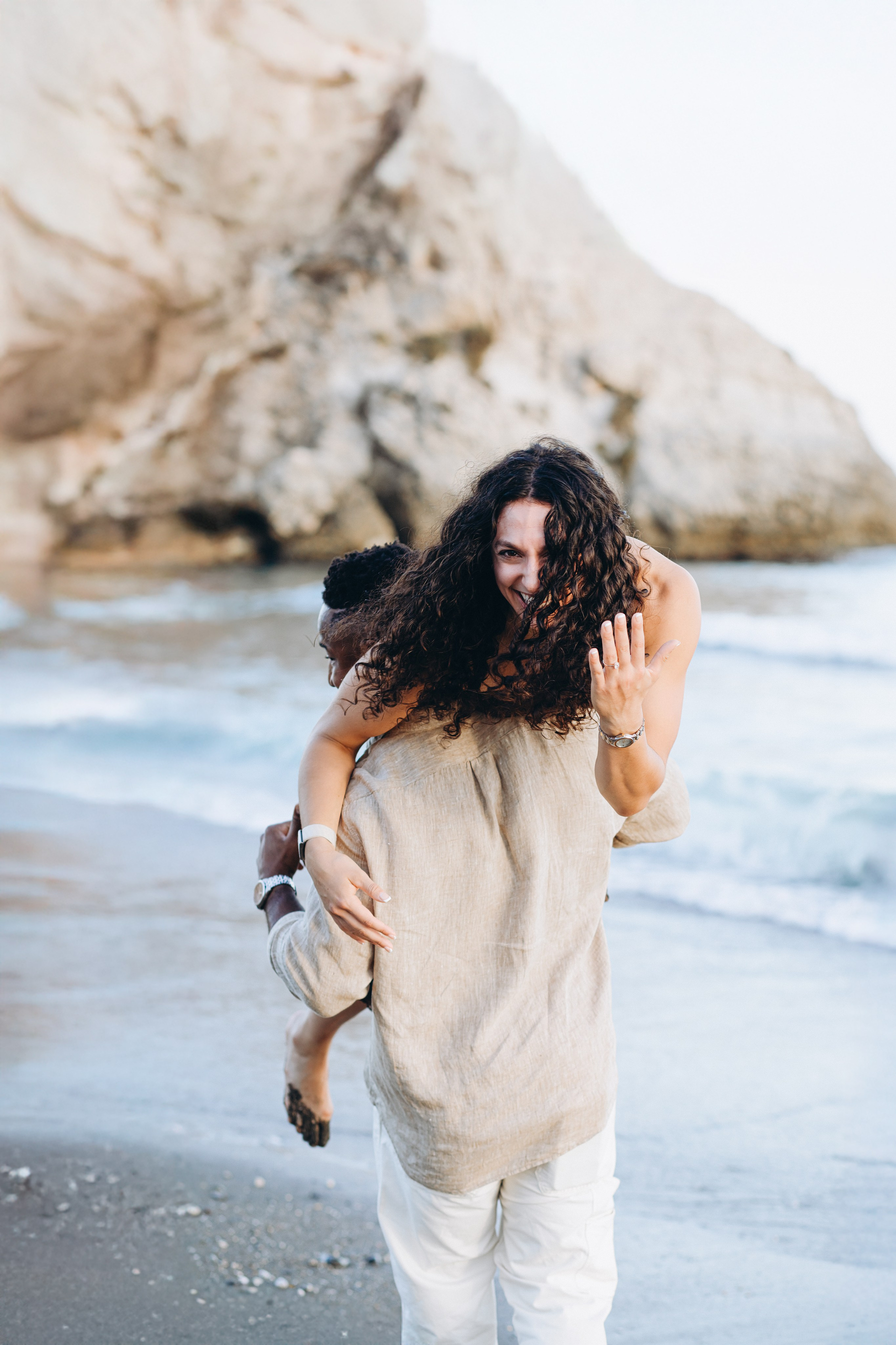 Sesión divertida y espontánea de historia de amor en la playa de Valencia, España, con una pareja feliz disfrutando de un paseo a caballito junto al mar — perfecto para quienes buscan sesiones fotográficas divertidas, naturales y románticas en Valencia y España.