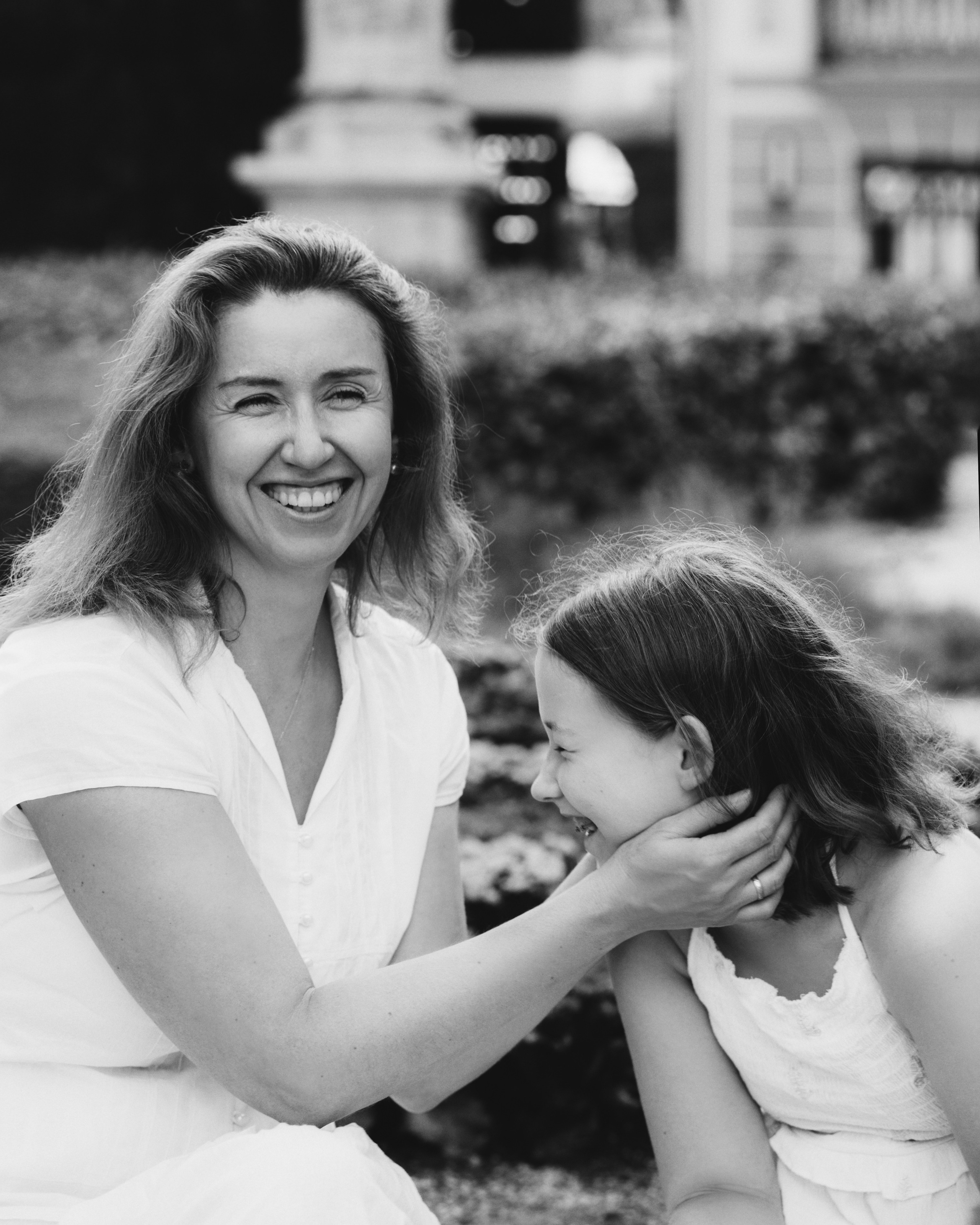 Retrato familiar en blanco y negro capturando un momento espontáneo de risa y afecto entre una madre sonriente y su hija en Valencia, España — ideal para mostrar emociones genuinas en sesiones familiares en Valencia y España.