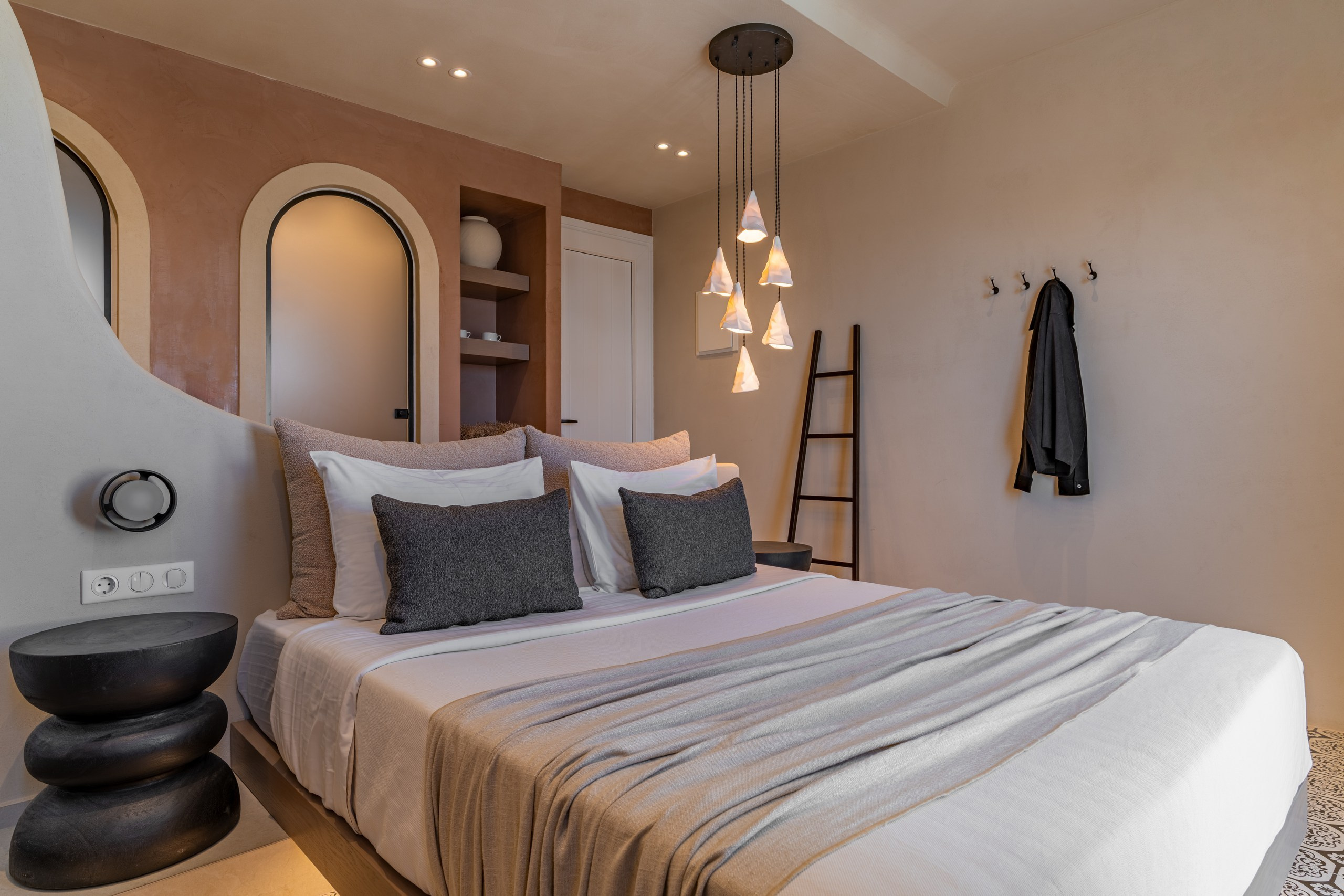 The essence of island tranquility: A cozy double bed setting with minimal pendant lighting and a decorative wooden ladder. Interior photography by George Katsaelis for the Atlantic residence.