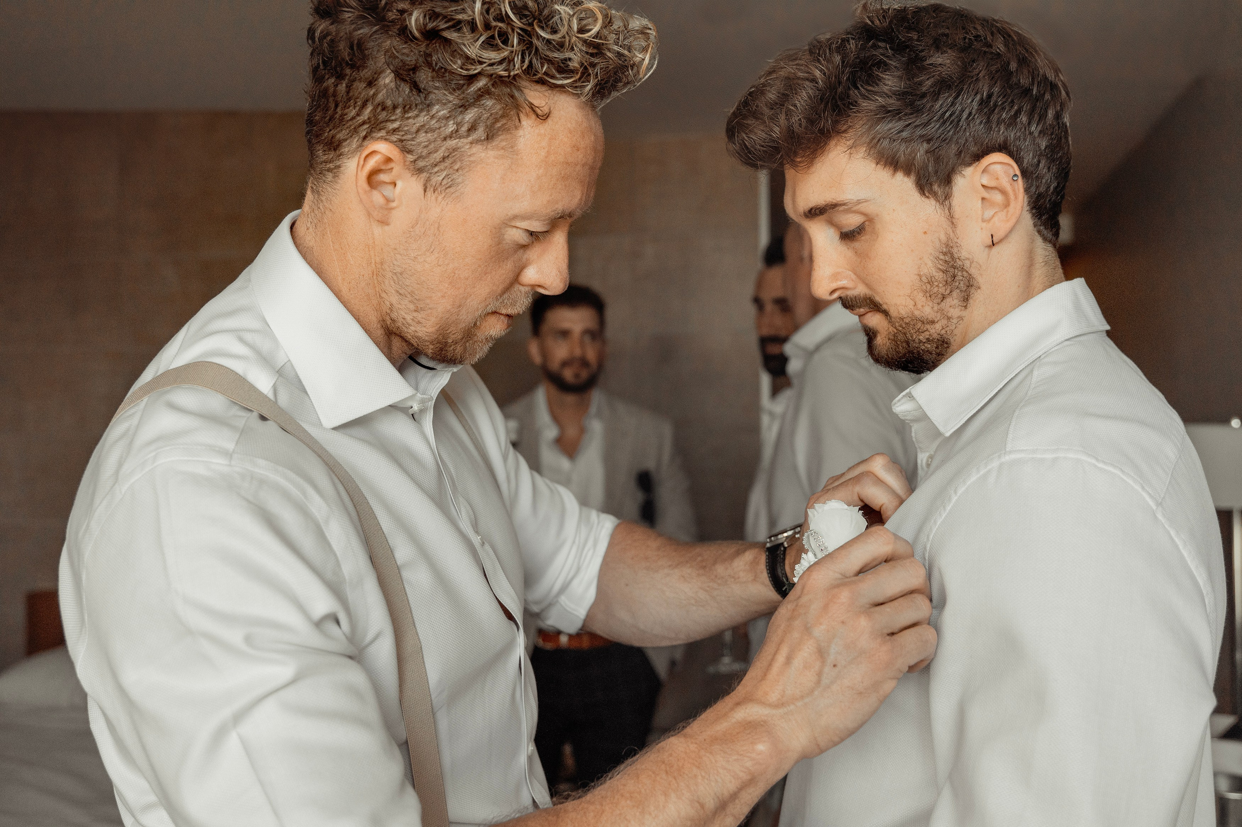 The groom's best man is putting a boutonniere to his friend. Rhodes, Greece.