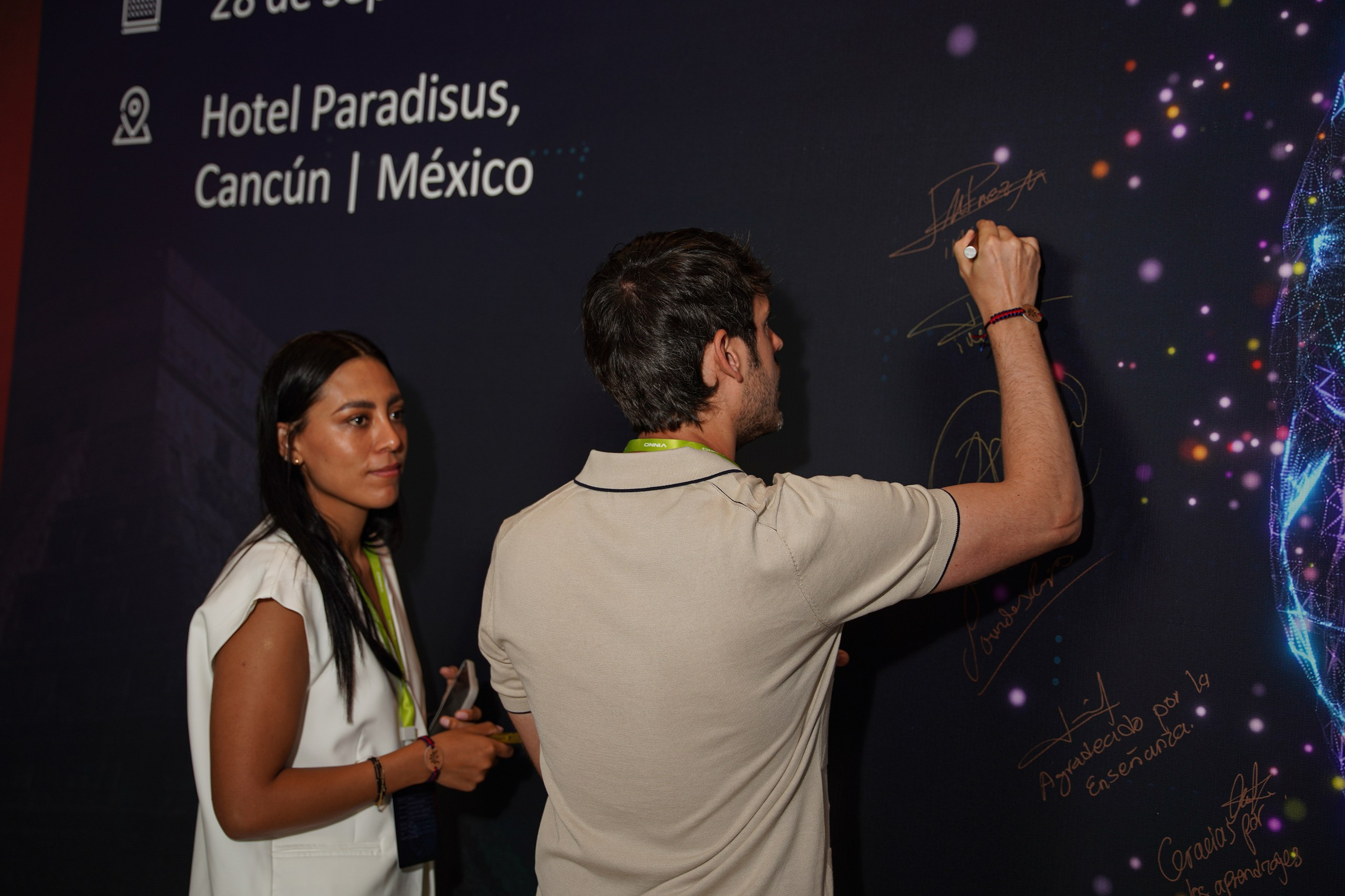 Participant signing branded event wall during corporate celebration.