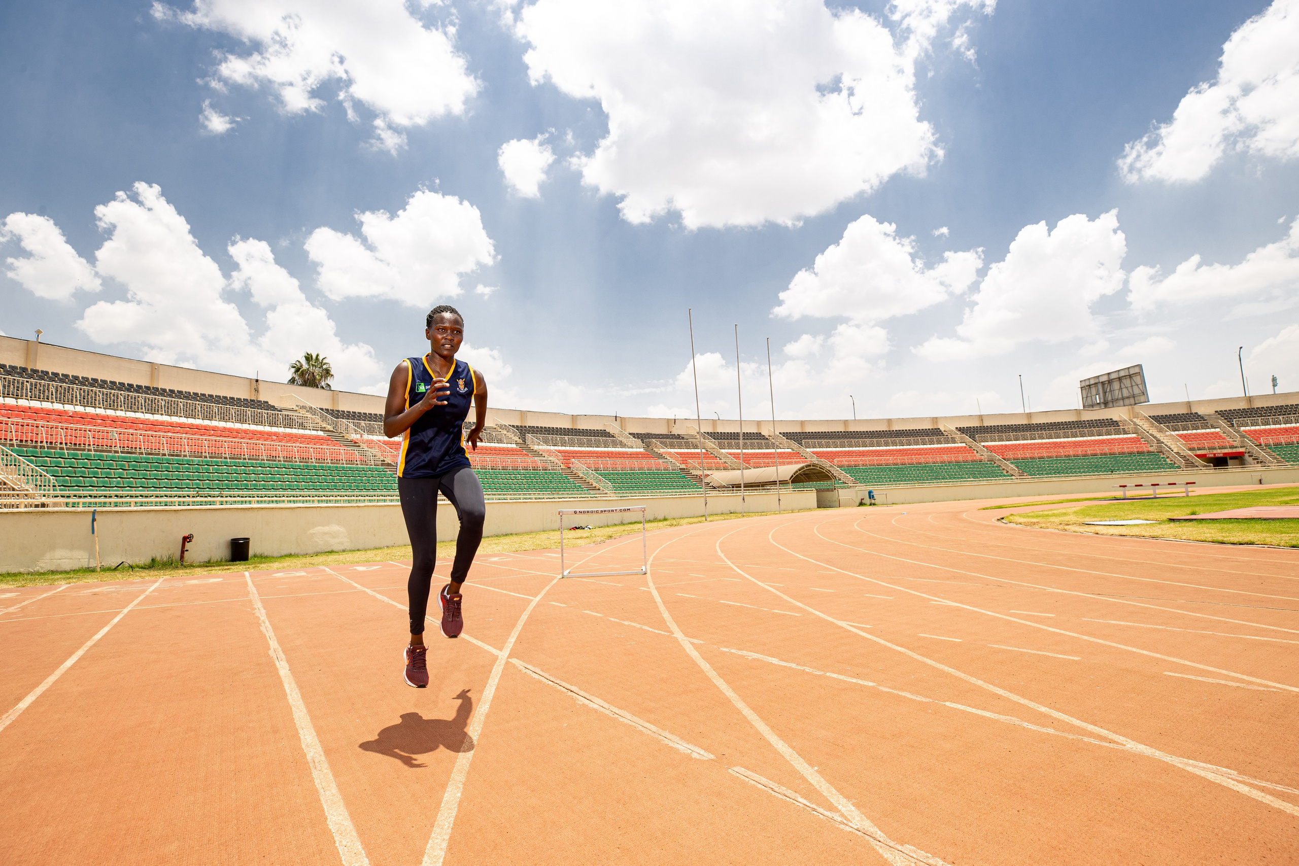 A wide shot of an athlete as they warm up at the tracks in Nyayo Stadium. Documentary photography
