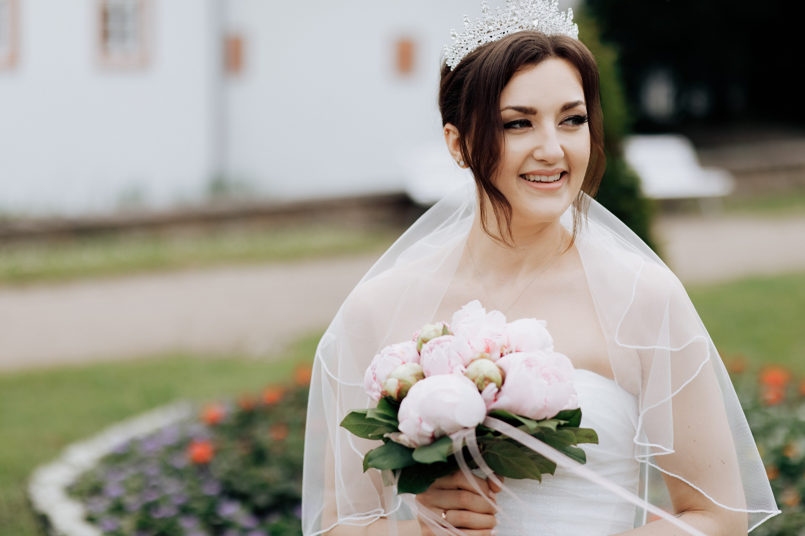 Die Braut schaut in die Ferne und lächelt in einer hellen, fröhlichen Frühlingsatmosphäre.