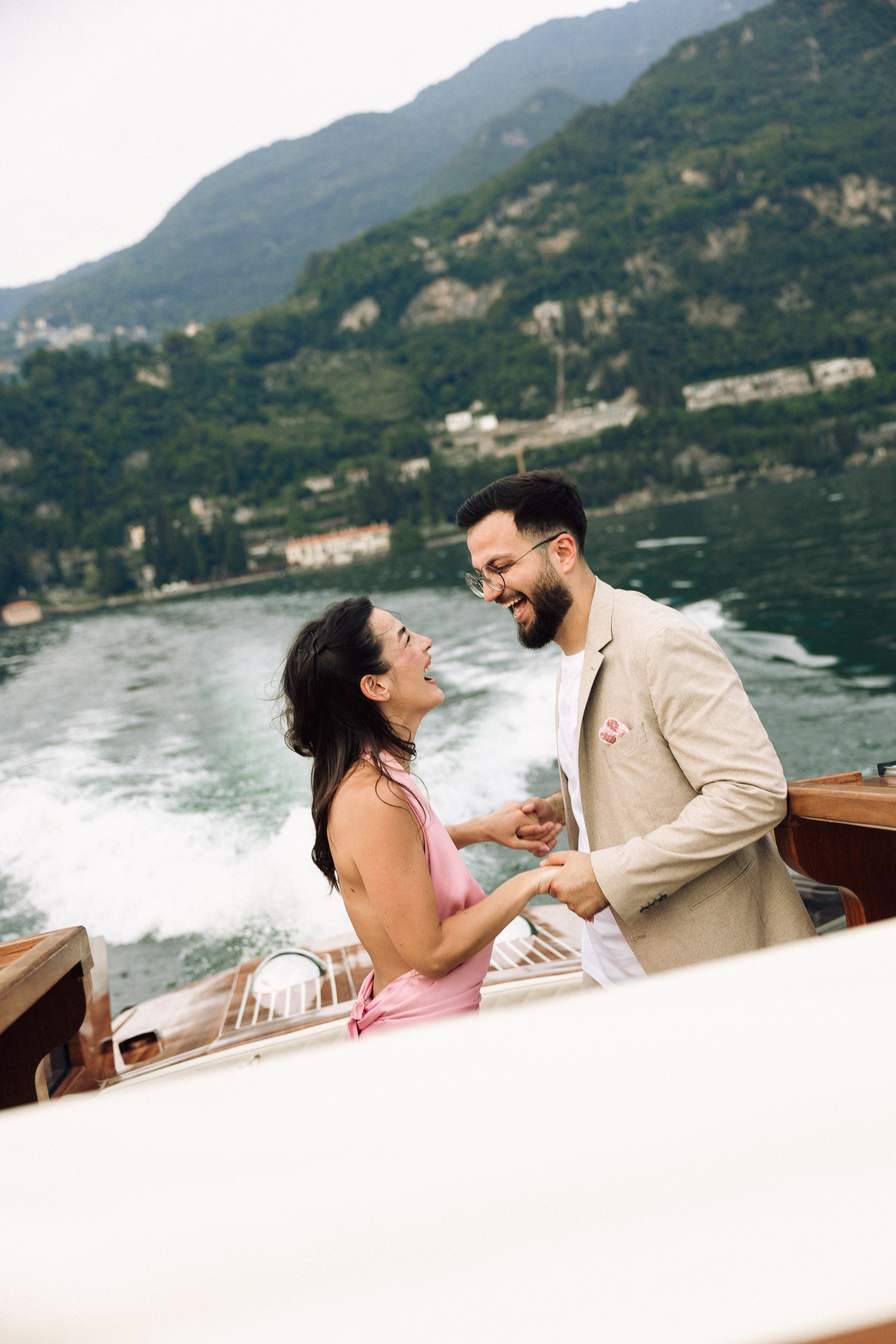Couple smiling together on a boat surrounded by the scenery of Lake Como