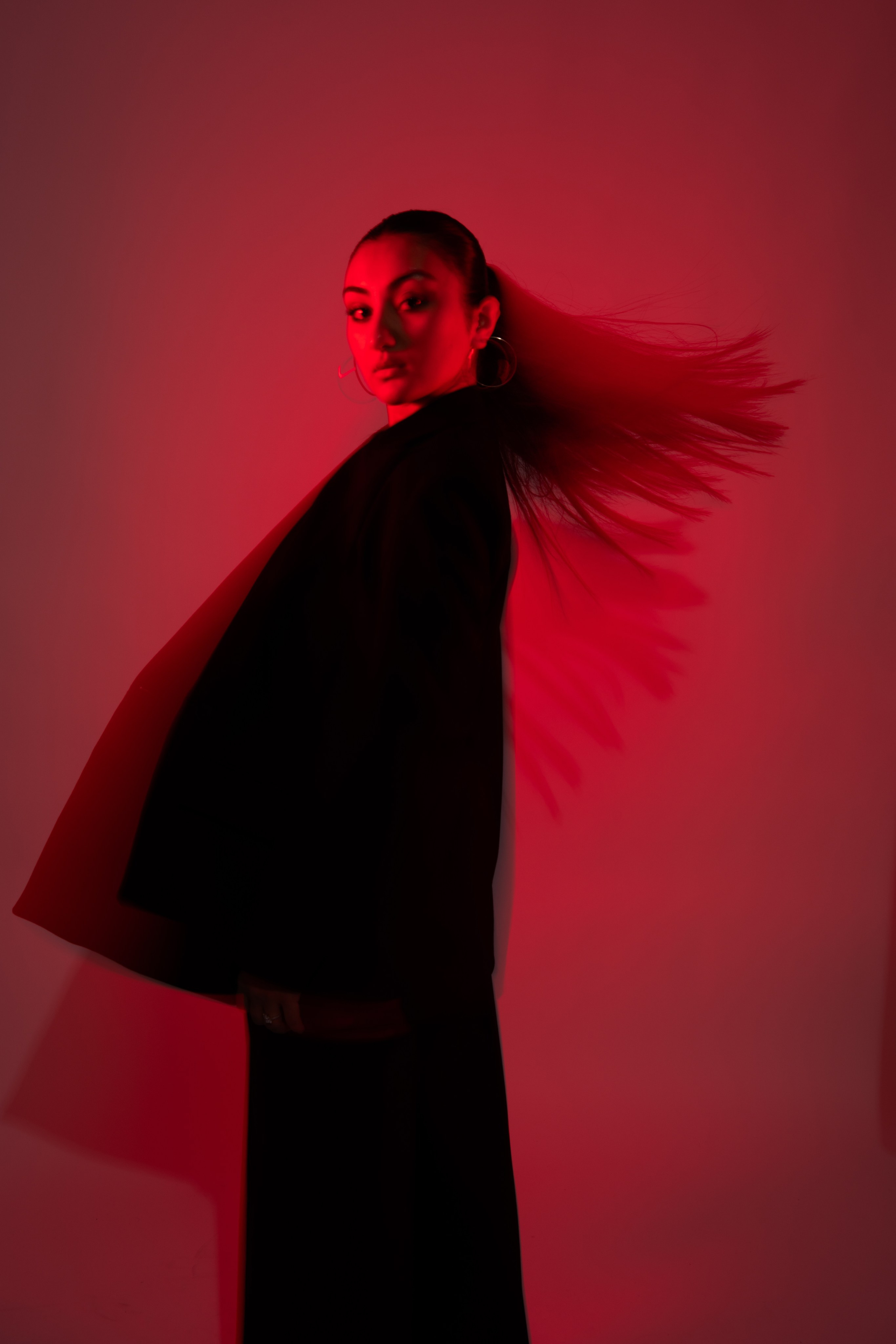 Red Fashion Shoot with Bold Studio Lighting – A powerful fashion portrait of a model in a red outfit, posed against a vivid red backdrop, highlighted by strong studio lighting that accentuates the texture of the garments.