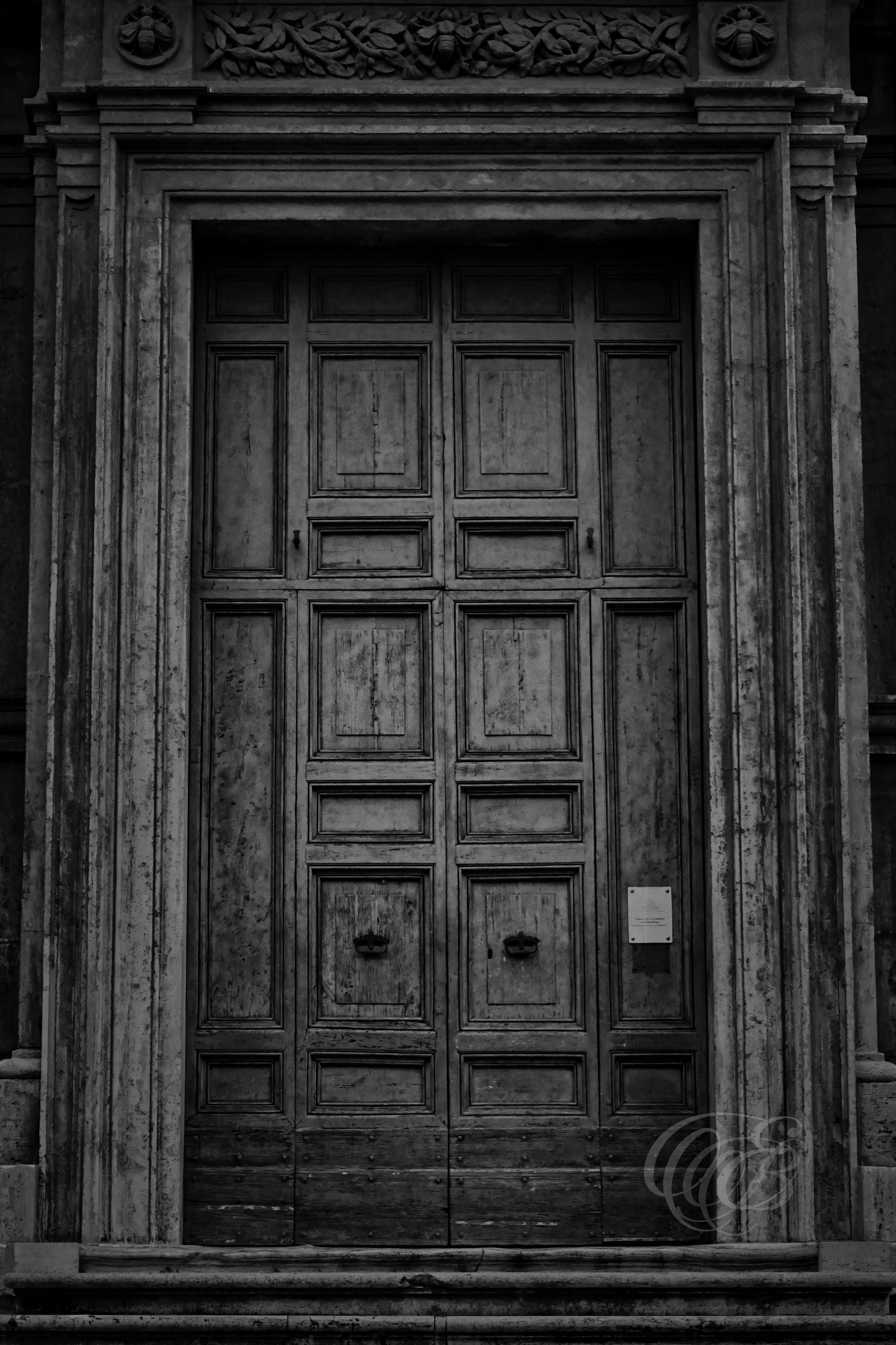 Street Photography — Rome, Italy — Old Door — B&W — Black and white study of an old Roman door, emphasizing weathered wood, aged textures, traditional craftsmanship, and the marks left by time — Eduardo Bartoli Photography.