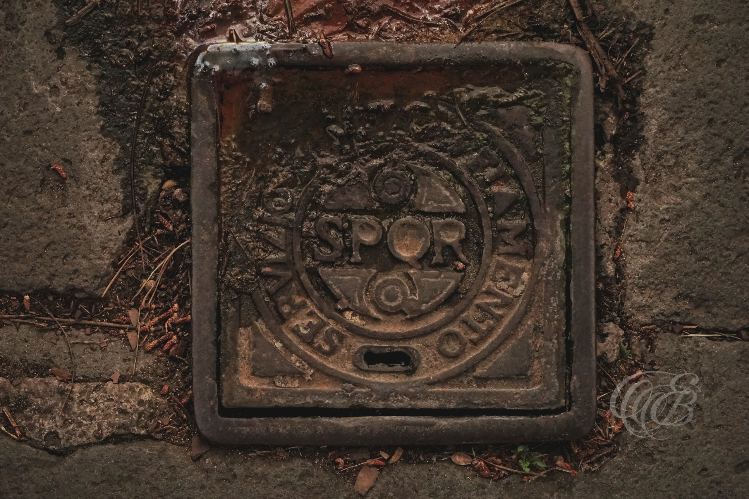 Street Photography — Rome, Italy — S.P.Q.R. — Metal water utility cover bearing the historic S.P.Q.R. inscription on a Roman street, an enduring civic symbol of the Senate and People of Rome found throughout the city’s public infrastructure — Eduardo Bartoli Photography.