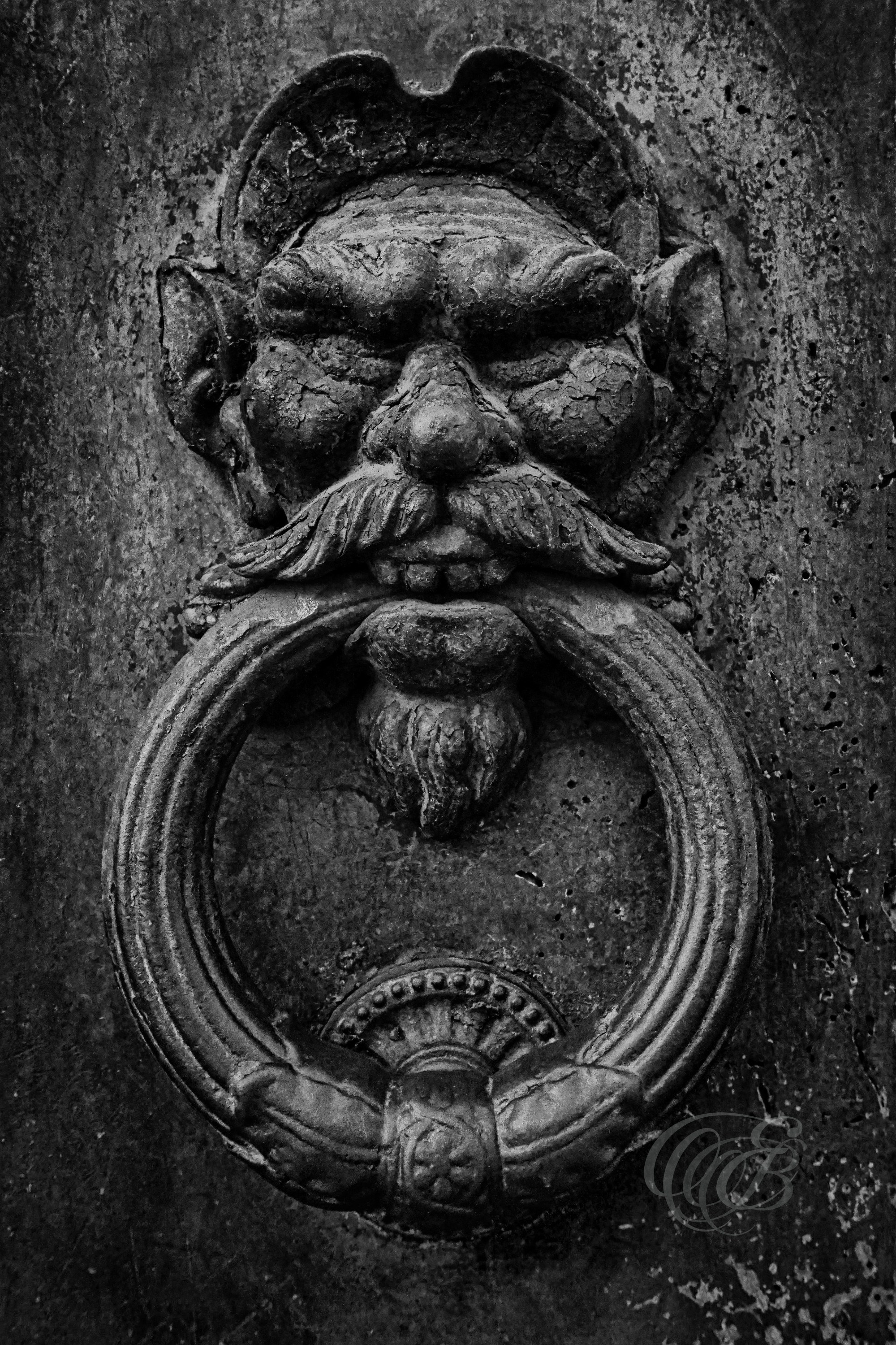 Street Photography — Rome, Italy — Old Door Knocker — B&W — Black and white study of an old door knocker in Rome, emphasizing traditional metalwork, aged textures, architectural detail, and traces of historic craftsmanship — Eduardo Bartoli Photography.