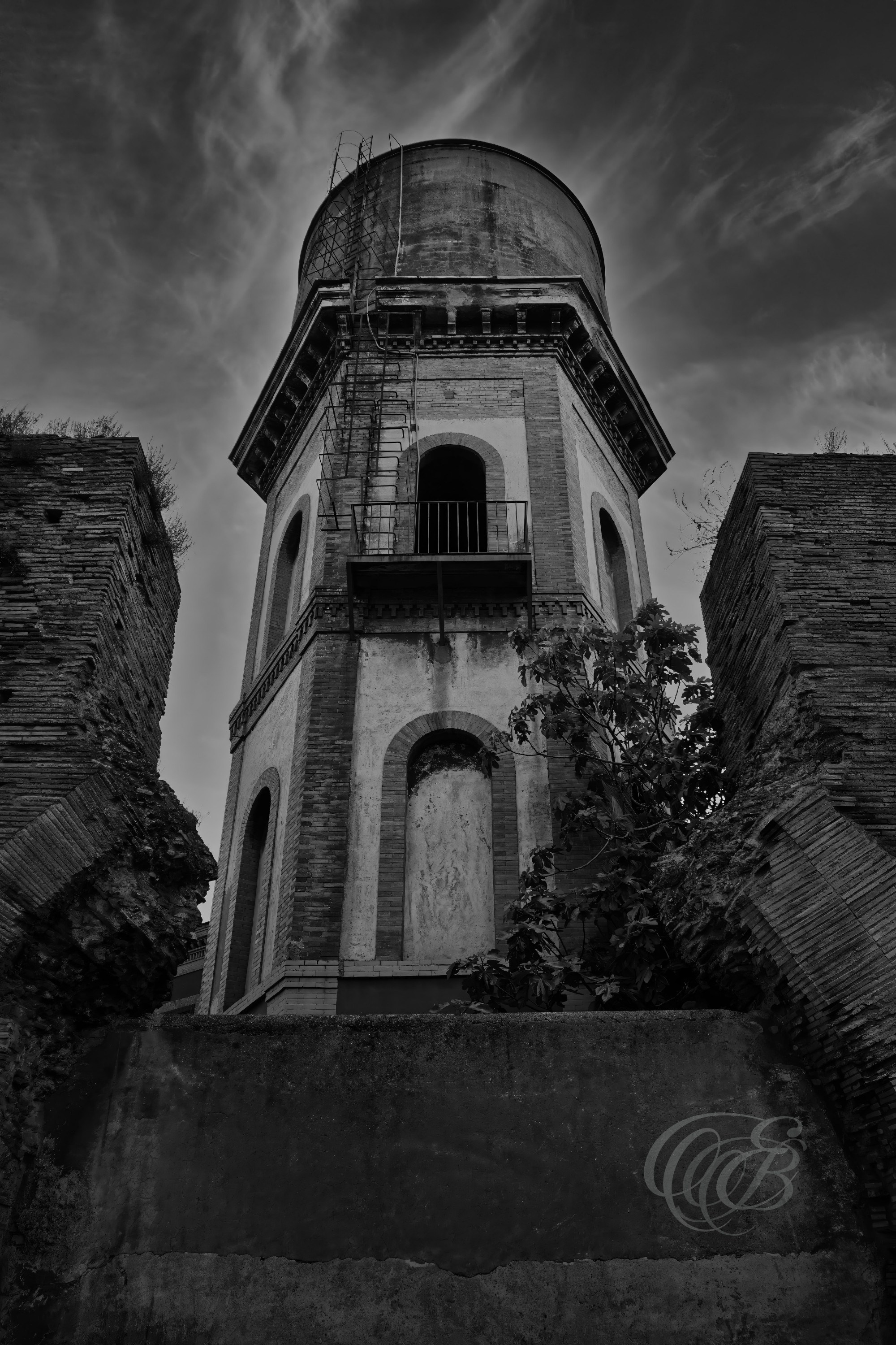 Street Photography — Rome, Italy — Water Tower — B&W — Black and white view of a Roman water tower, emphasizing functional architecture, geometric form, and the infrastructure woven into the everyday landscape of the city — Eduardo Bartoli Photography.