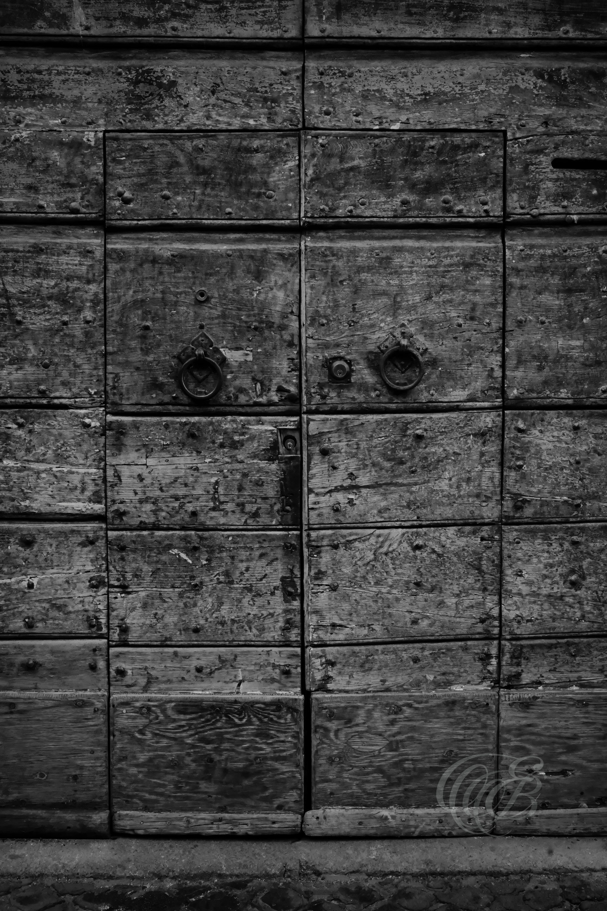 Street Photography — Rome, Italy — Rustic Old Door — B&W — Black and white study of a rustic old door in Rome, emphasizing weathered wood, traditional craftsmanship, aged textures, and the architectural character of the historic city — Eduardo Bartoli Photography.