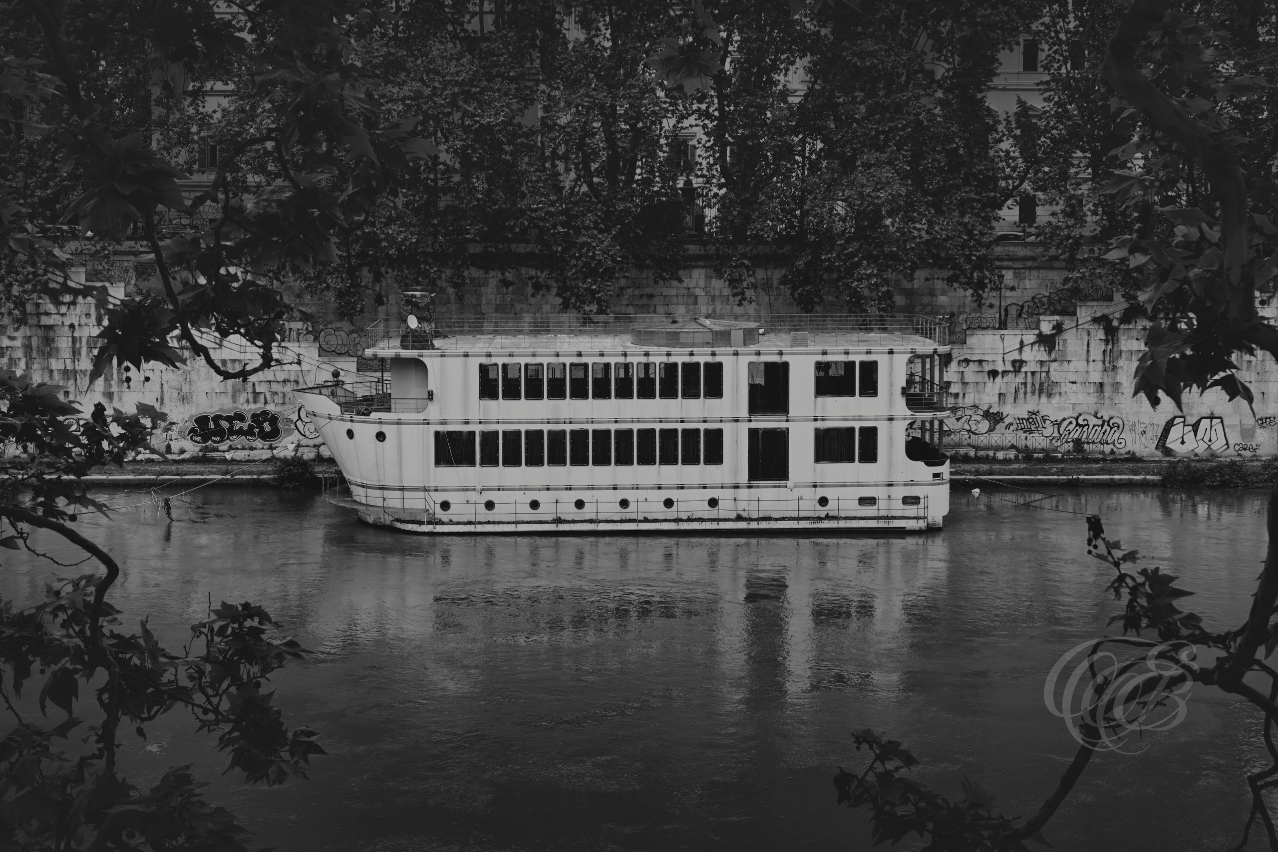 Street Photography — Rome, Italy — Boat Docked on the Tiber — B&W Matte — Matte black and white view of a boat docked along the Tiber River in Rome, emphasizing river life, tonal textures, historic navigation, and the city’s enduring relationship with its ancient waterway — Eduardo Bartoli Photography.