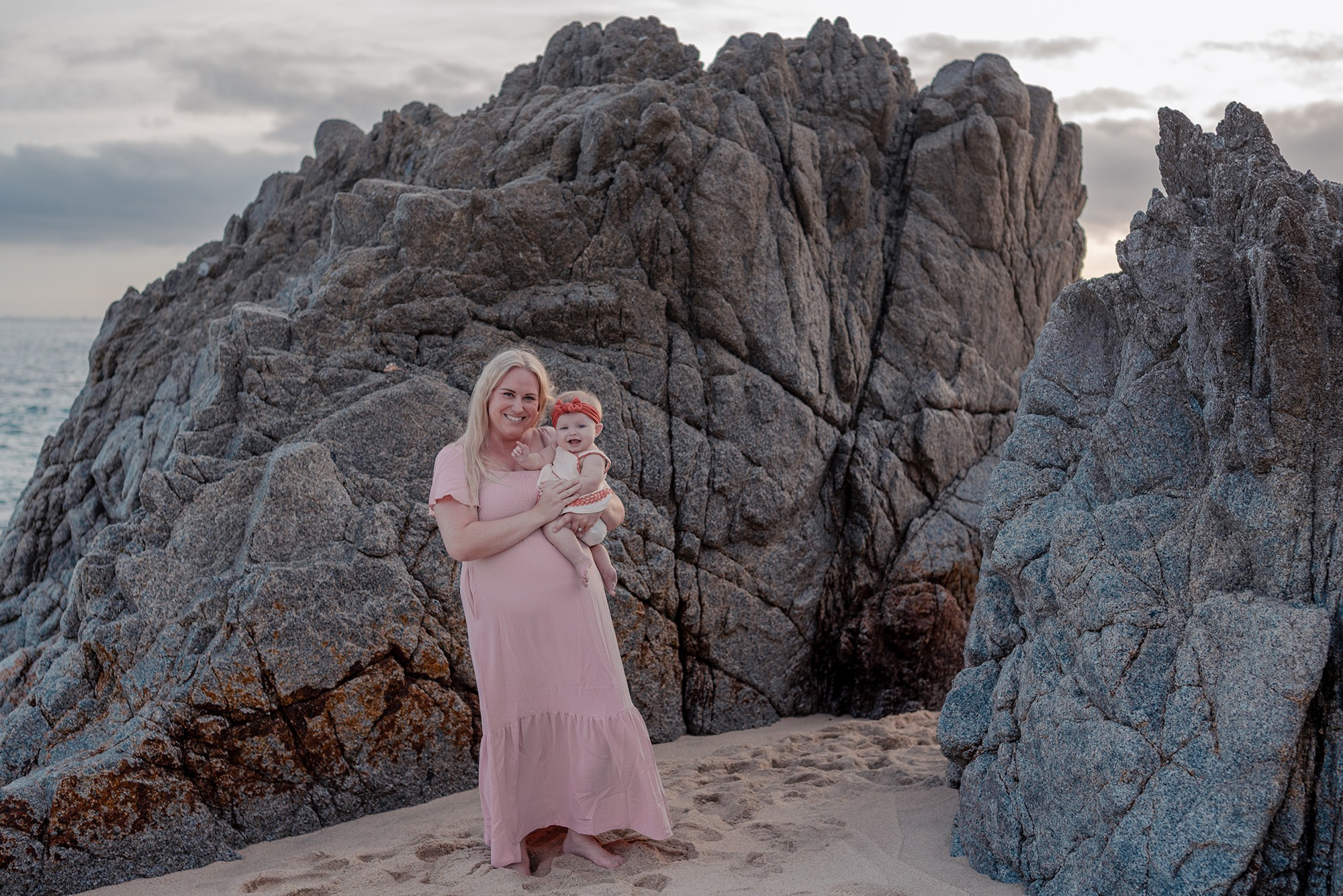 Family standing on the iconic rock formations at Playa Monumentos Cabo San Lucas during winter golden hour session