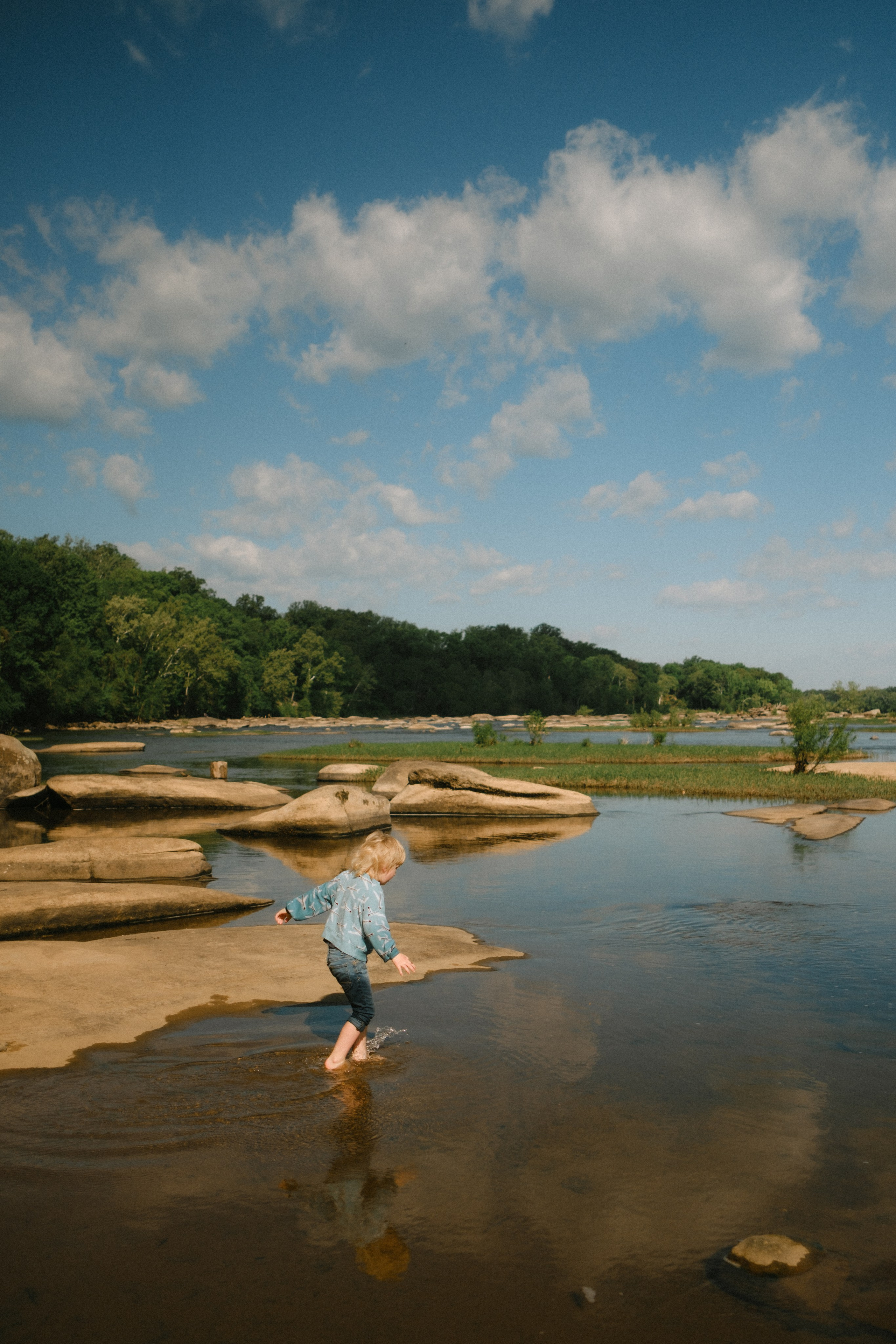 Artistic photo capturing a bit, standing in James River, skyline and water reflection during documentary family session at Pony Pasture in Richmond, VA 