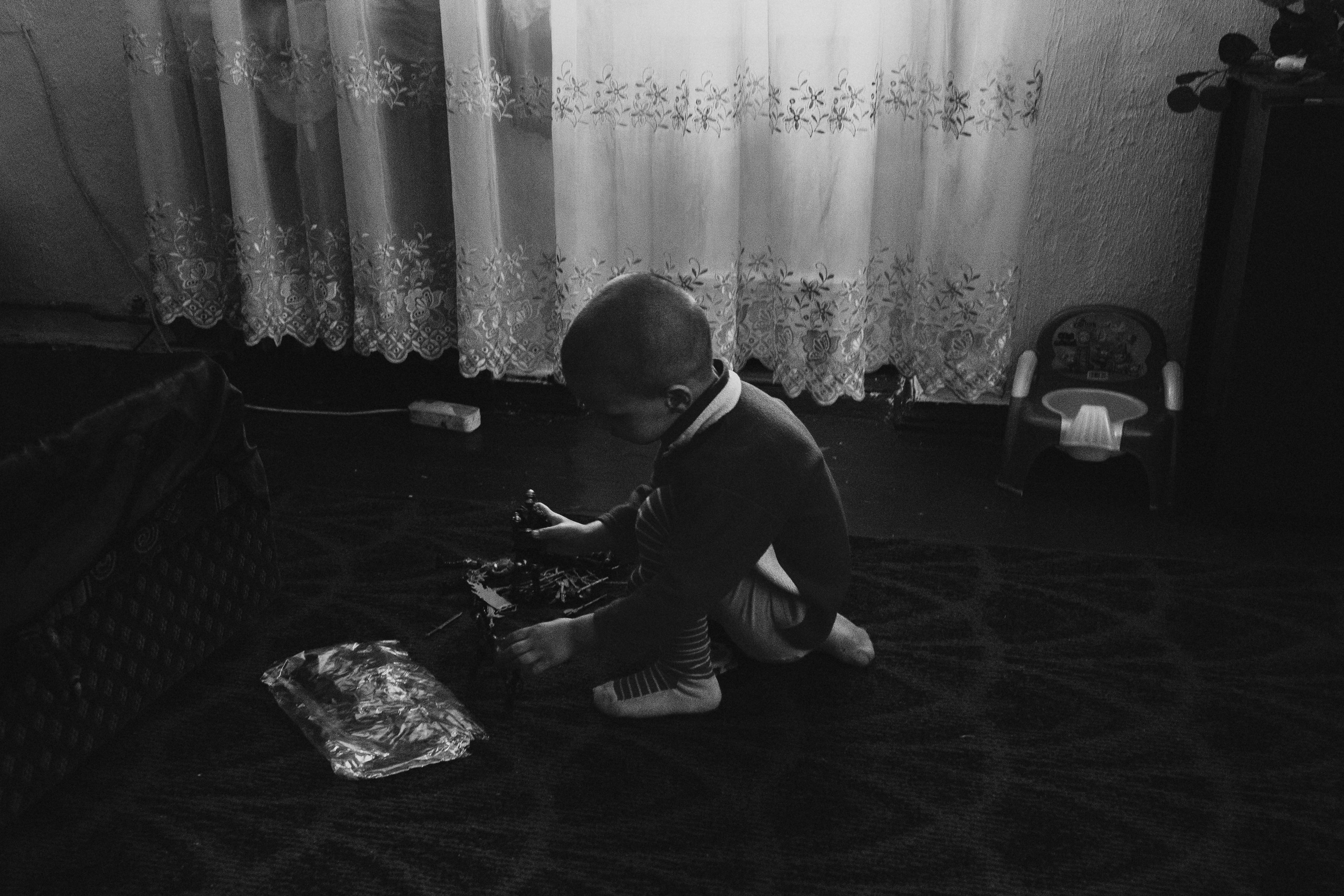 чёрно-белая социальная документальная фотография портрет бедность ребенок играет игрушки Фотограф в Ирландии