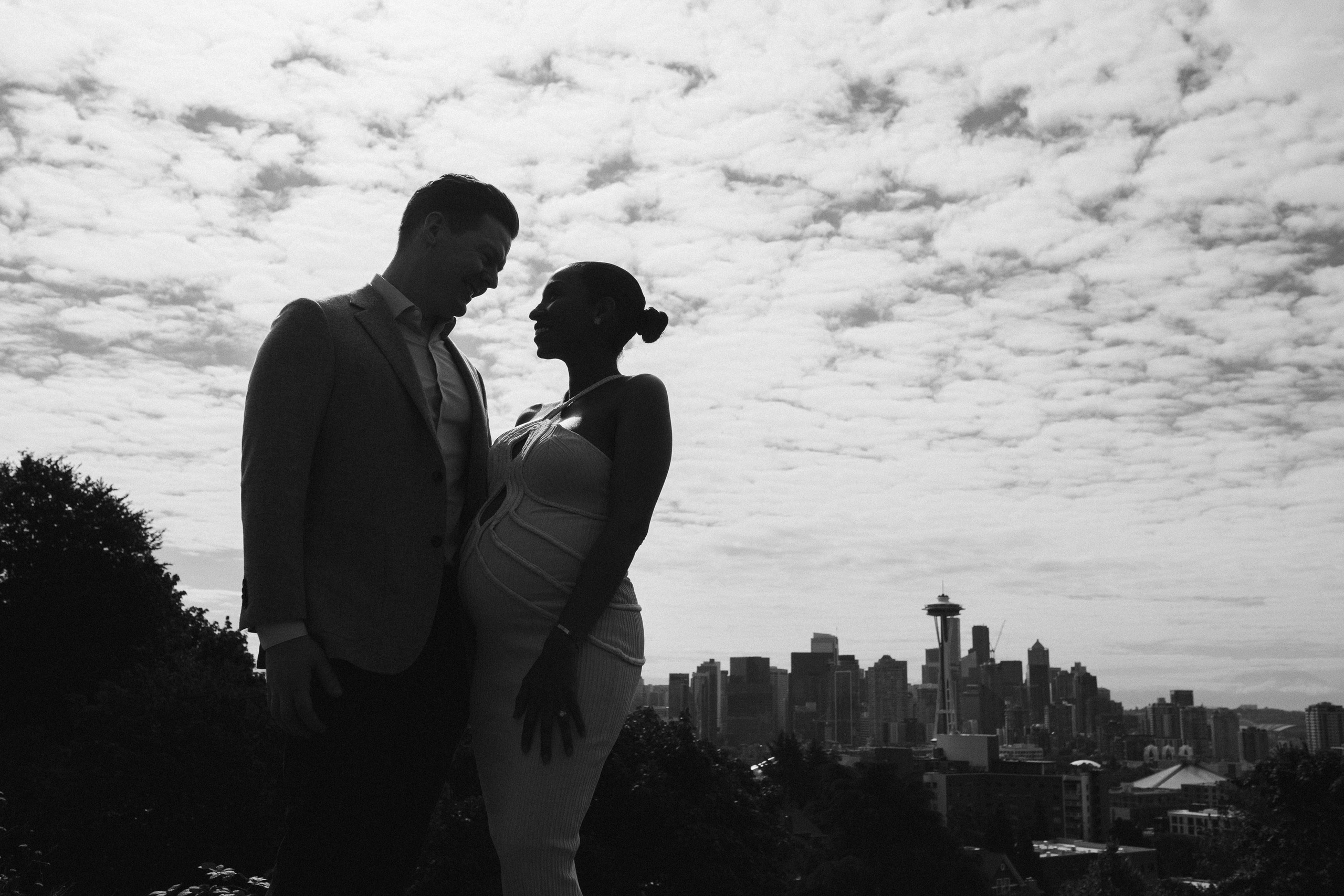 Couple kissing under cloudy sky, romantic black and white photo