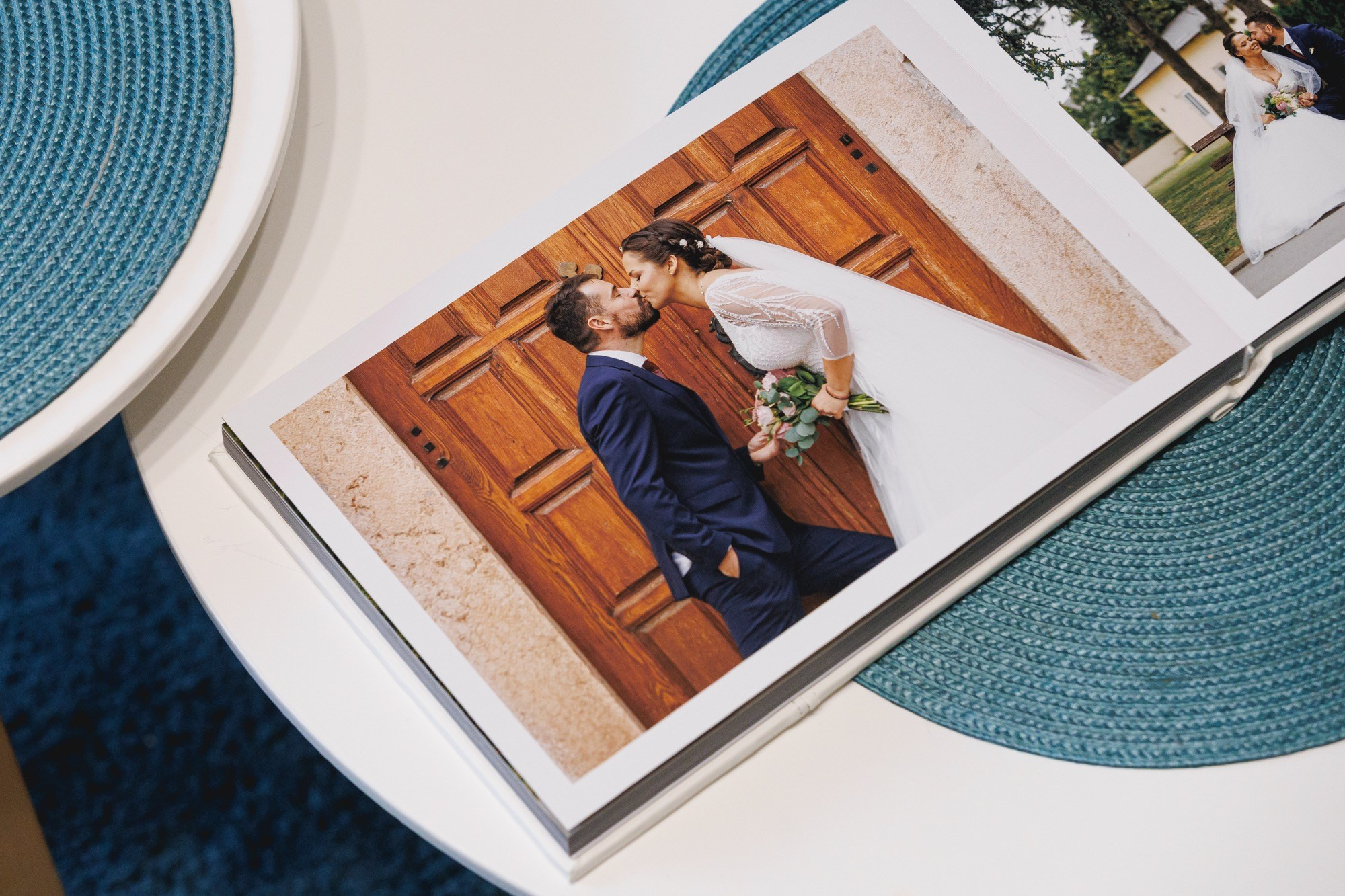 Detalj wedding book-a sa fotografijom poljupca mladenaca ispred drvenih vrata, premium štampa fotografija.
