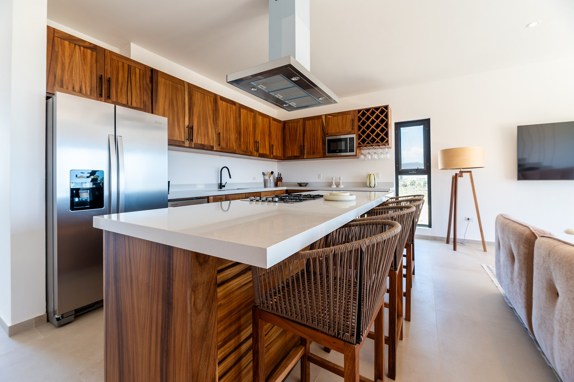 Modern kitchen bar area in Cabo San Lucas – dining stools, refrigerator, stove and hood, interior real estate photography