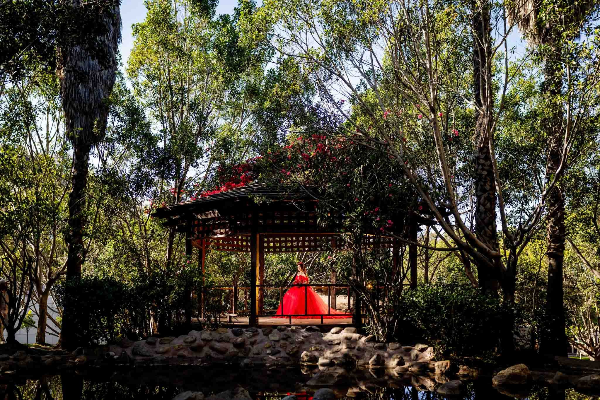 Sesion de quinceanera en quiosco de parque en Tijuana con vestido rojo elegante y fotografia profesional en exterior