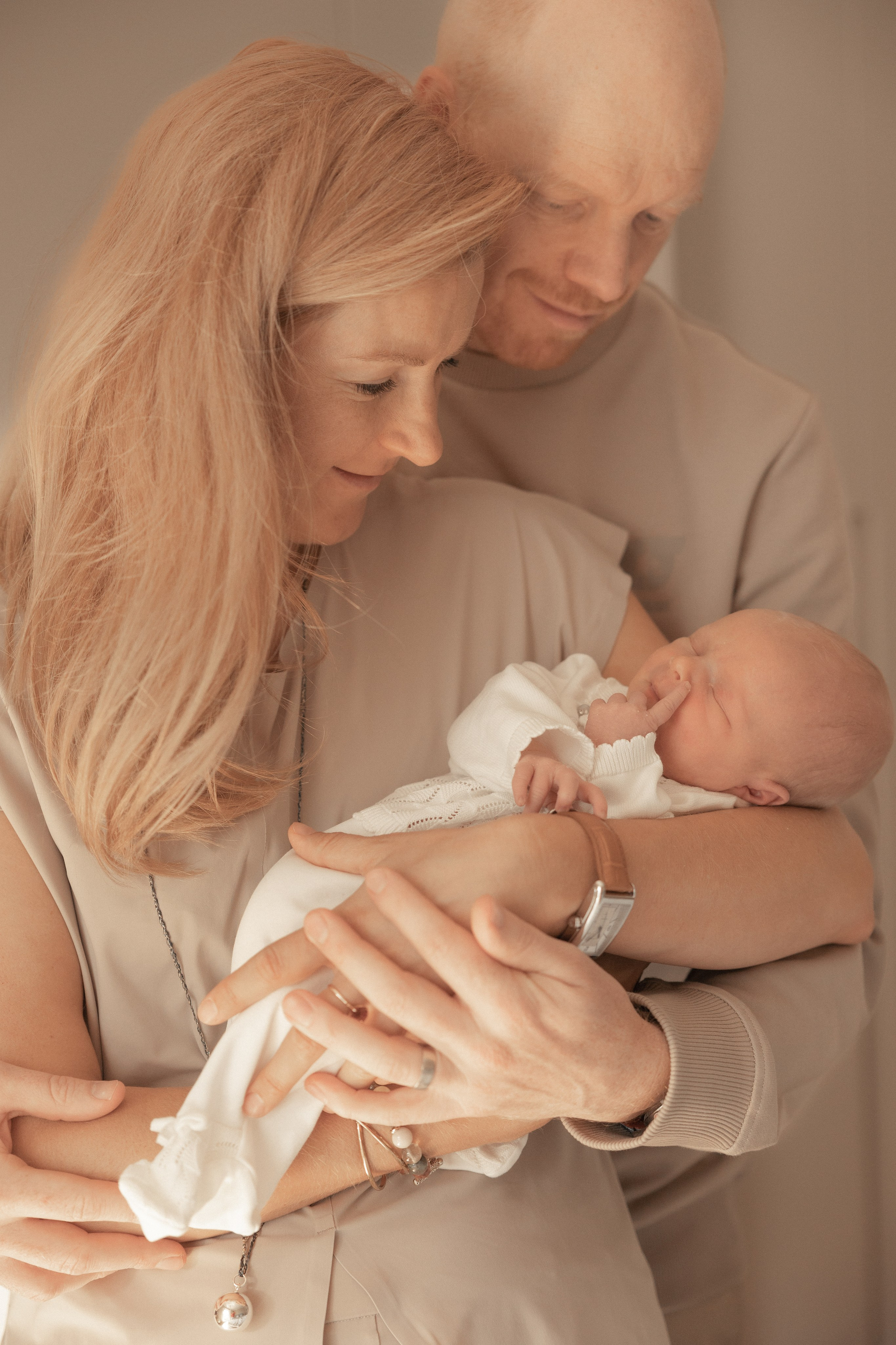 Eltern halten ihr Neugeborenes in liebevoller Umarmung – zartes, warmes Familien-Fotoshooting in Salzburg