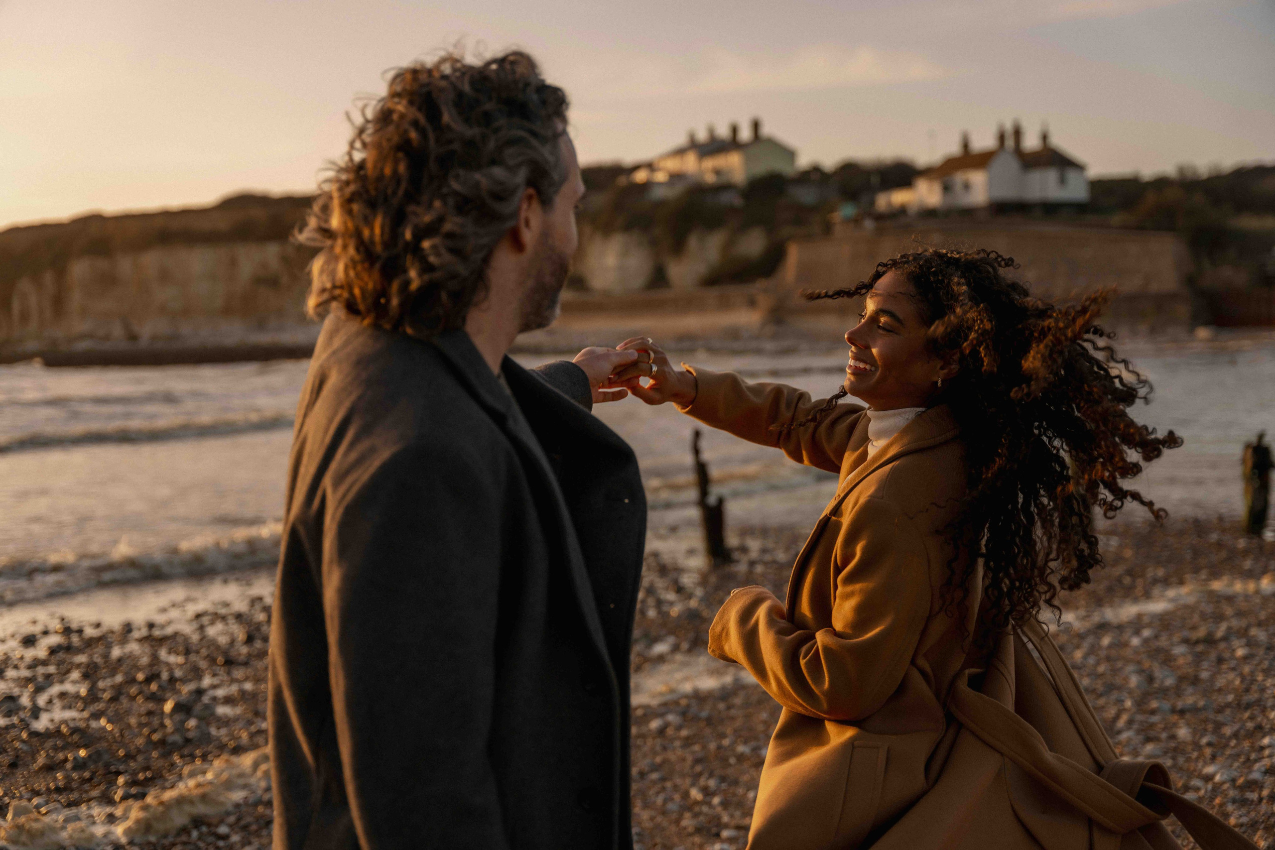 couple dancing on beach seven sisters engagement session uk candid movement sunset
