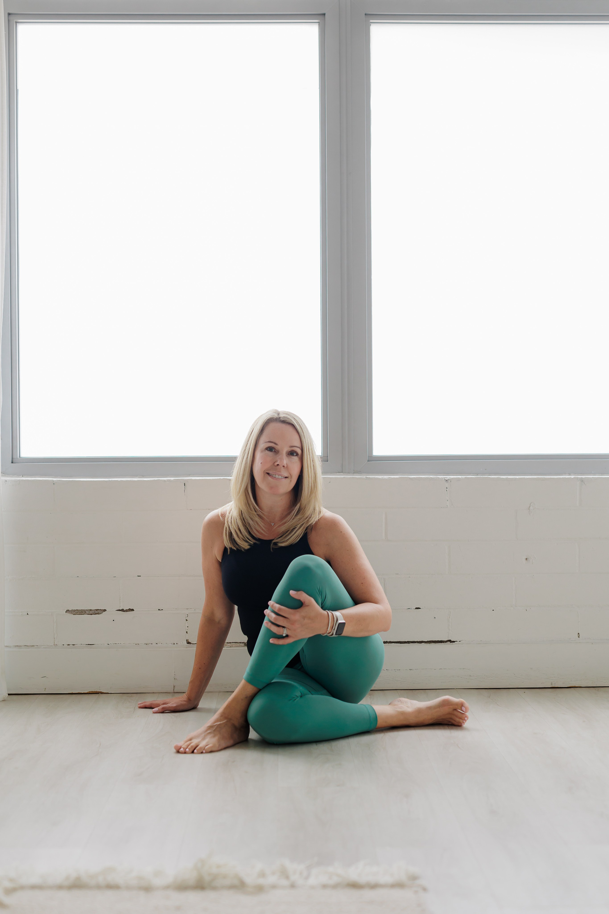 woman in green leggings in yoga pose on floor