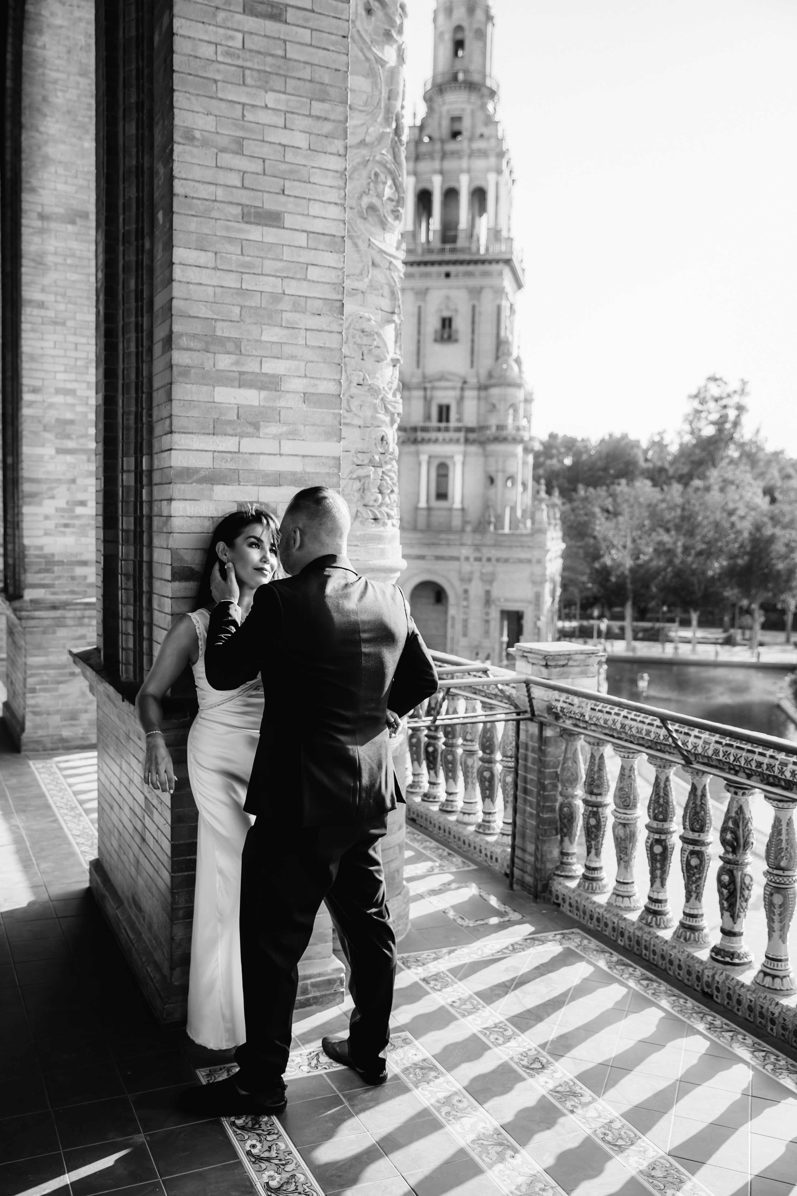 Romantic black and white wedding photo taken at Plaza de España in Sevilla, Spain — the groom gently touches the bride’s face as they share an intimate moment, perfect for couples searching for timeless and artistic wedding photoshoots in Seville or elegant destination wedding photography in Spain.
