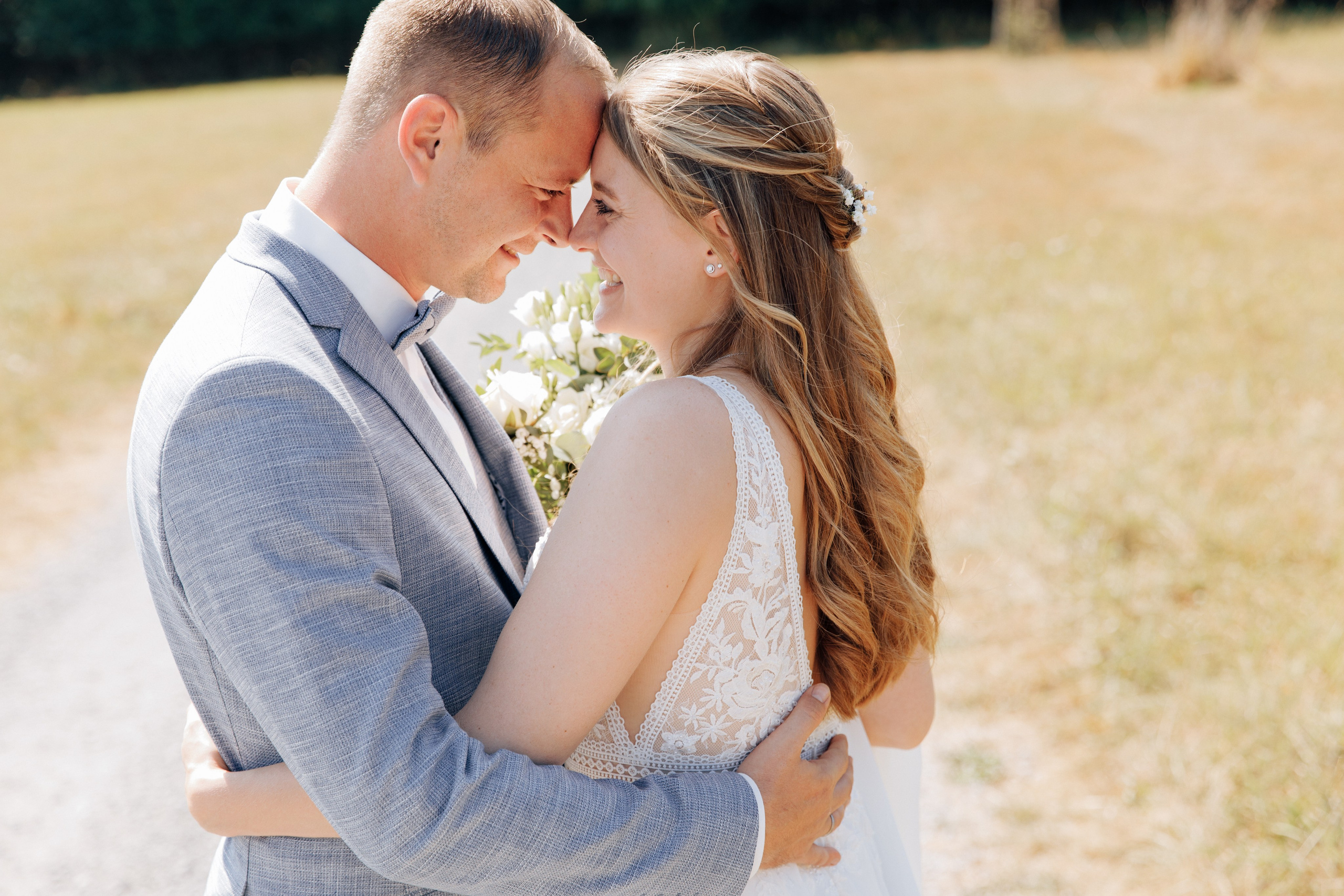 Bräutigam und Braut umarmen sich und schauen sich verliebt an.