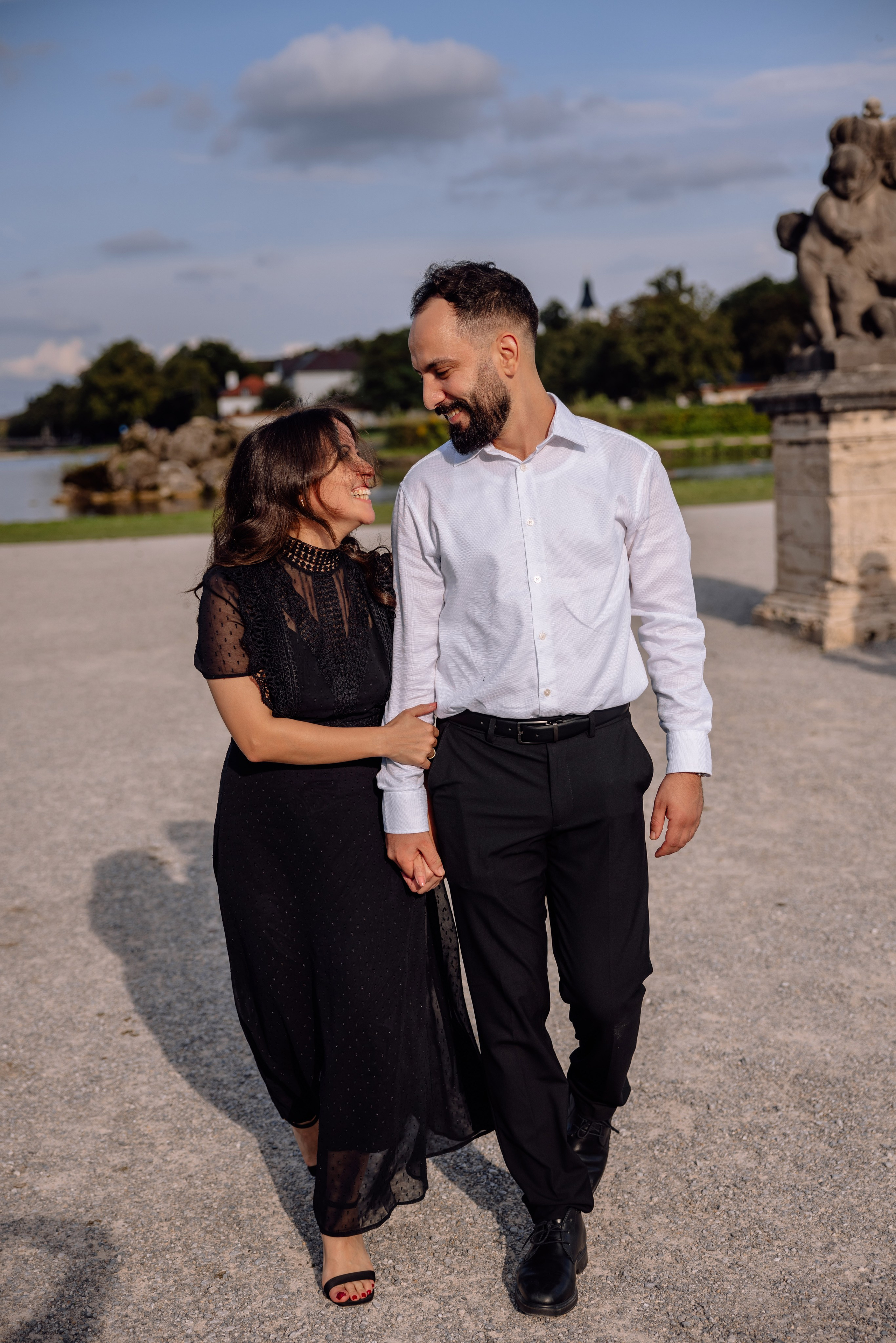 Verlobtes Paar läuft lachend und umarmt sich vor dem Schloss Nymphenburg