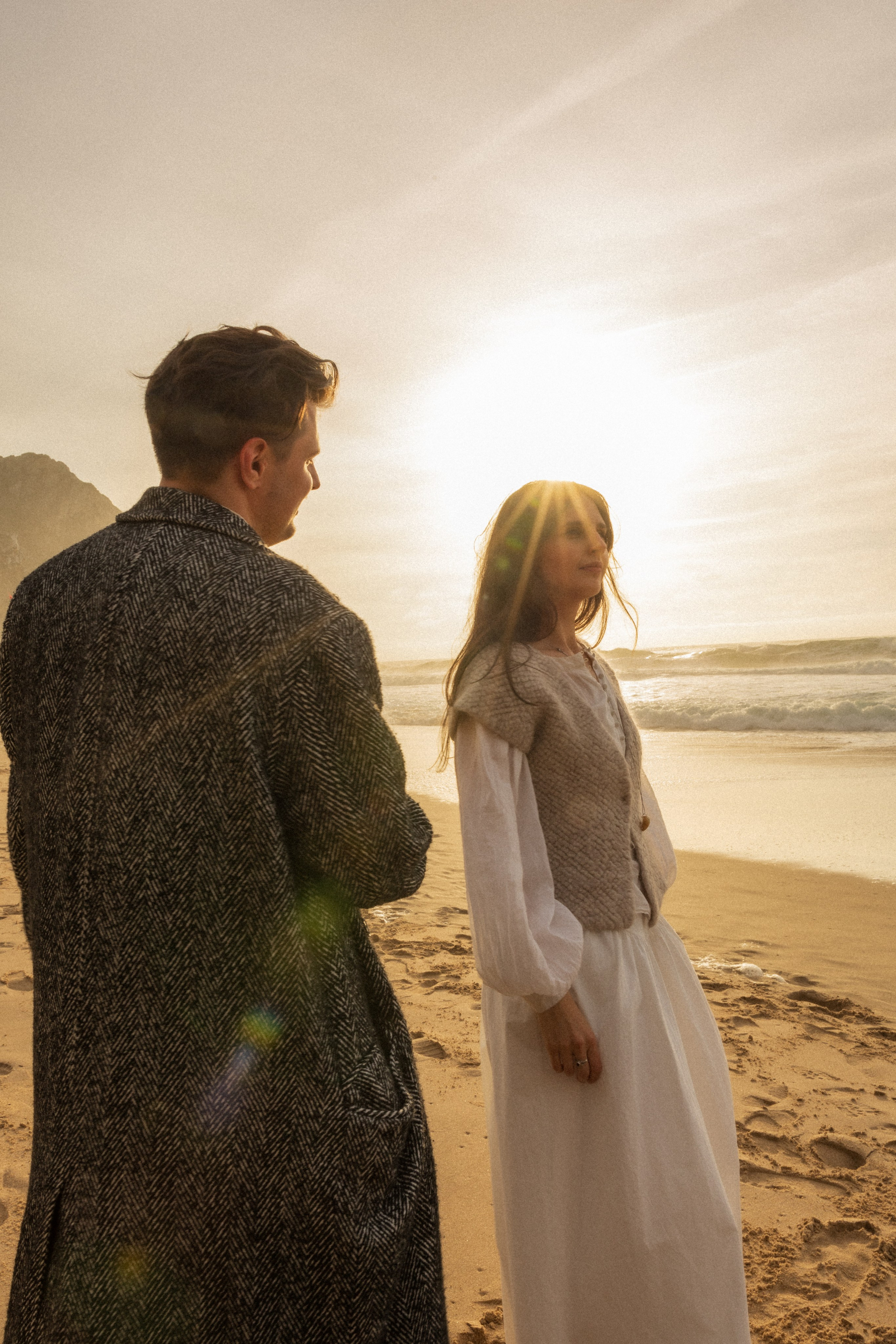 Couple holding hands and walking through a picturesque coastline in Portugal.