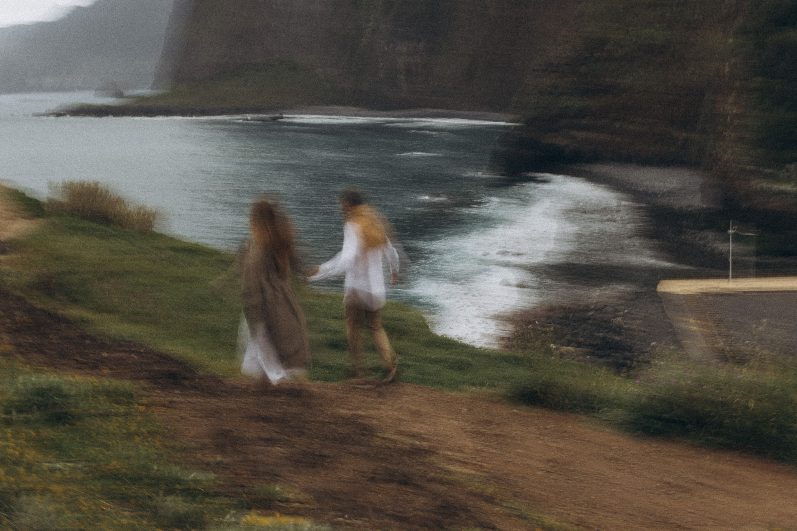 Beautiful engagement moment by the ocean in Madeira, Portugal, as one partner kneels to propose while waves crash in the background