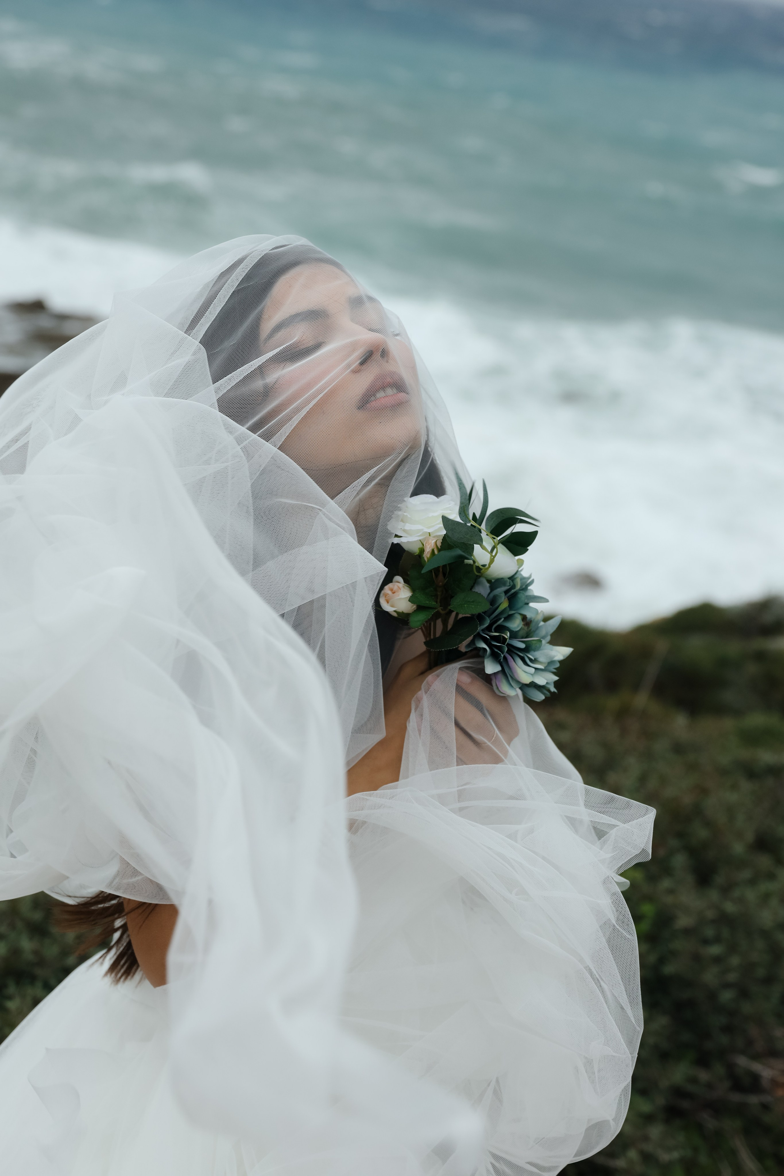 An art photo shoot of a girl in a wedding dress on the windy Kalithea beach in Rhodes, Greece