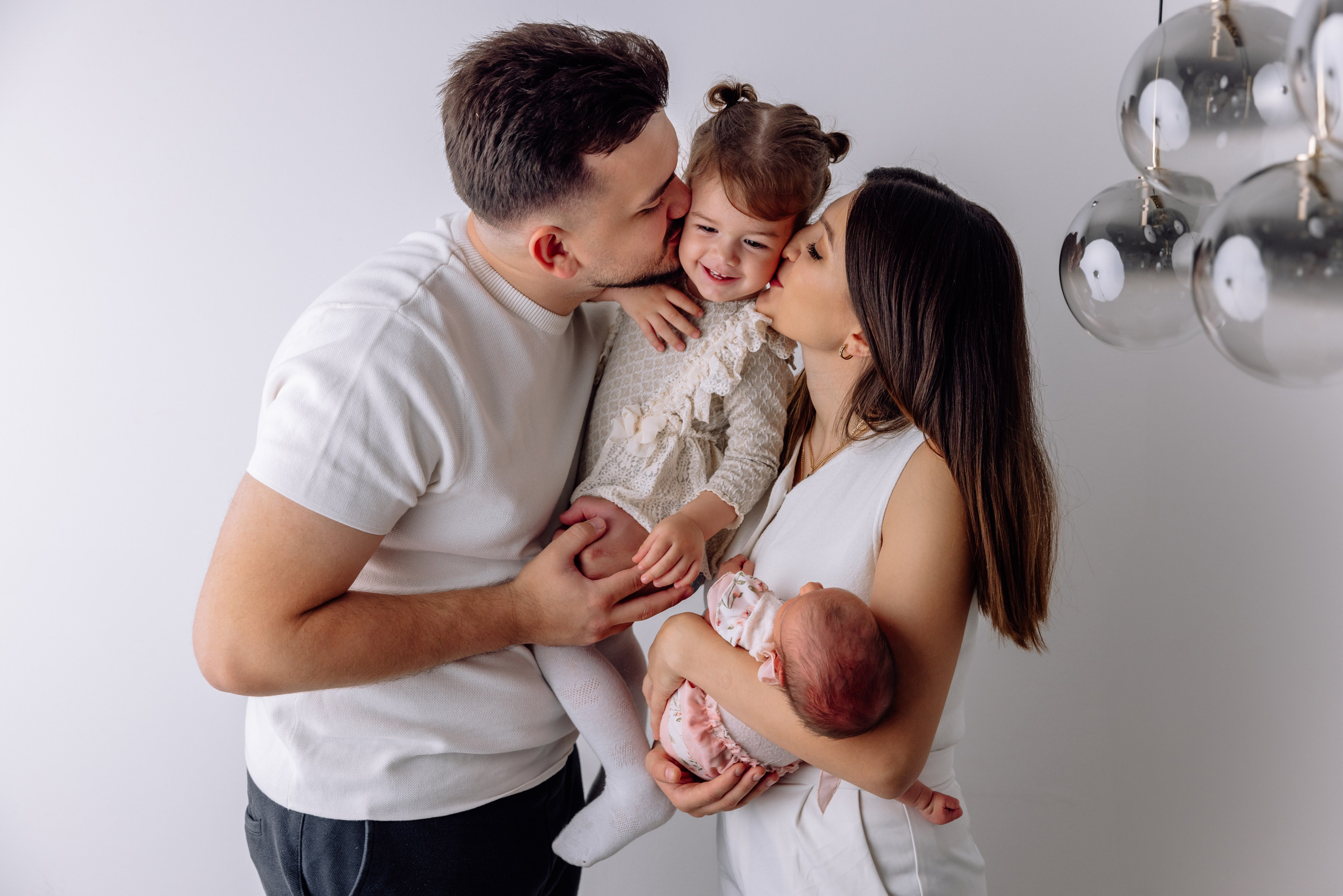 Vater und Mutter küssen Baby auf die Backen – liebevoller Moment in Karlsfeld